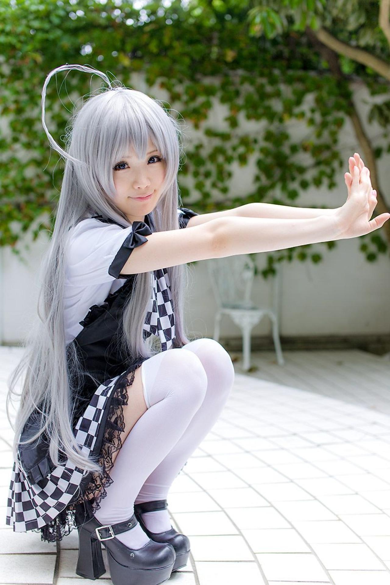 倉坂くるる侧身蹲在地上，双手手掌相叠，双臂向前推出，微笑