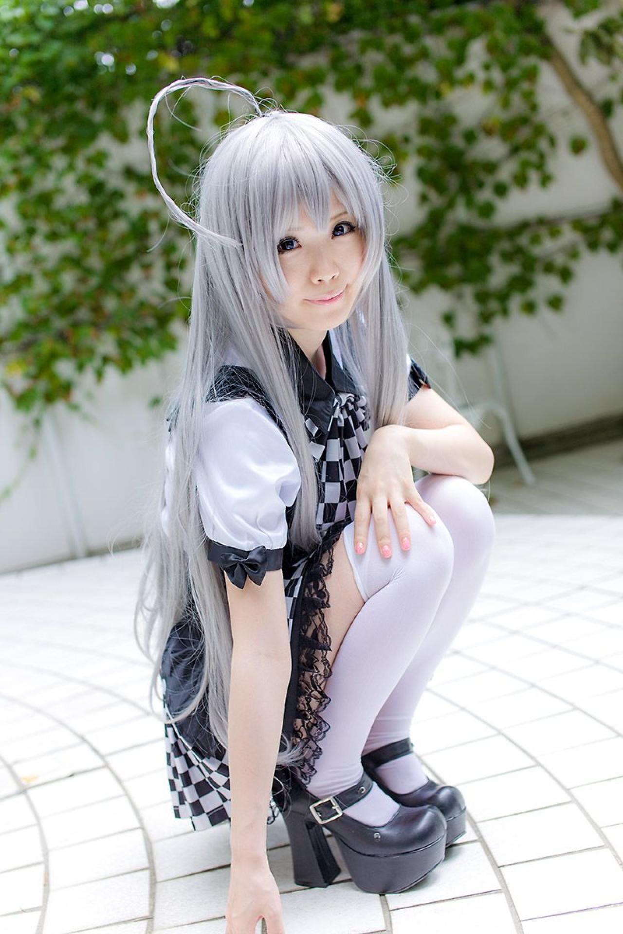 倉坂くるる蹲在地上，右手扶着地面，左手放在膝盖，微笑