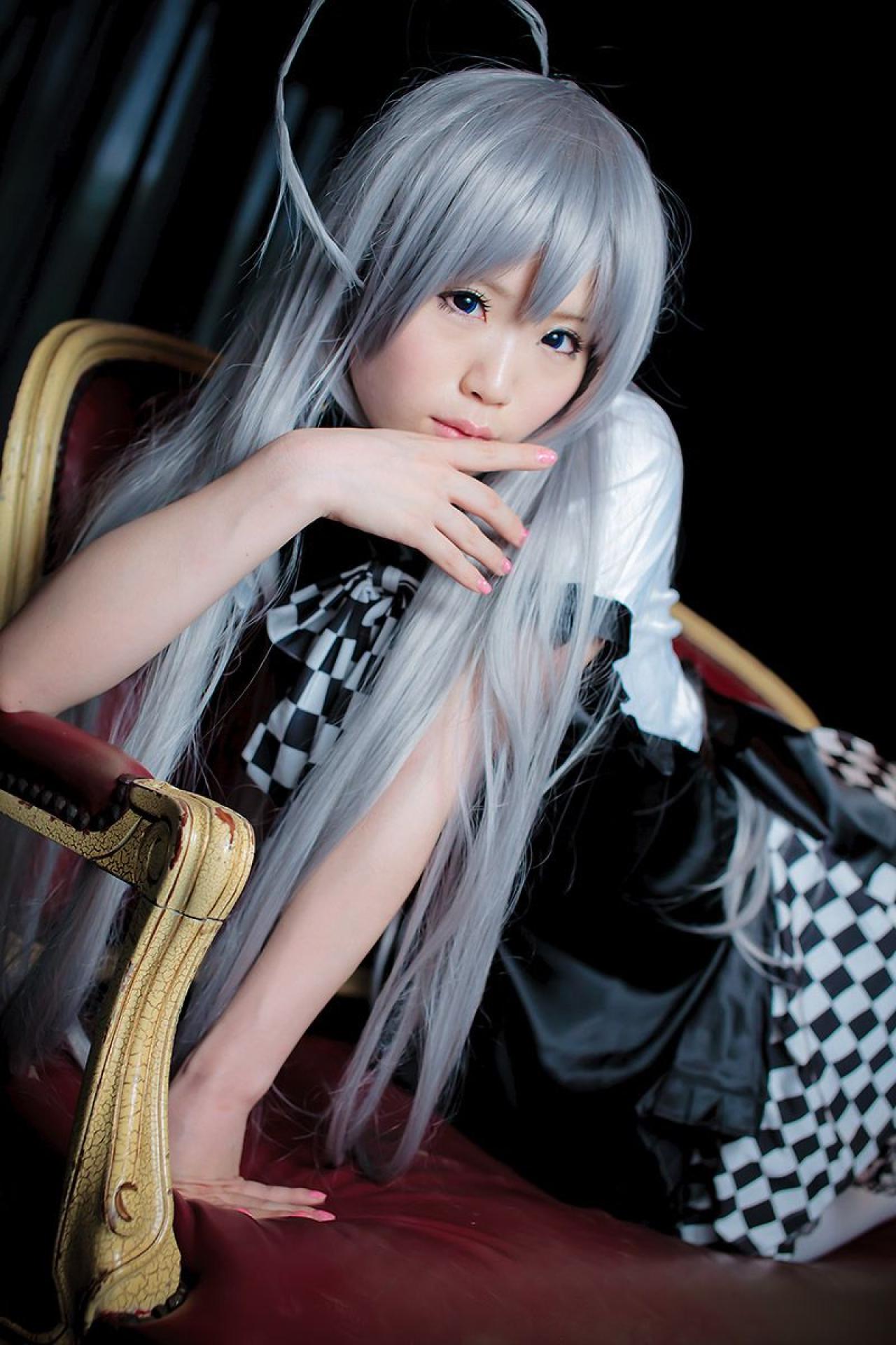 倉坂くるる扒在宫廷长椅上，左臂撑在坐垫上，右手食指贴着嘴角