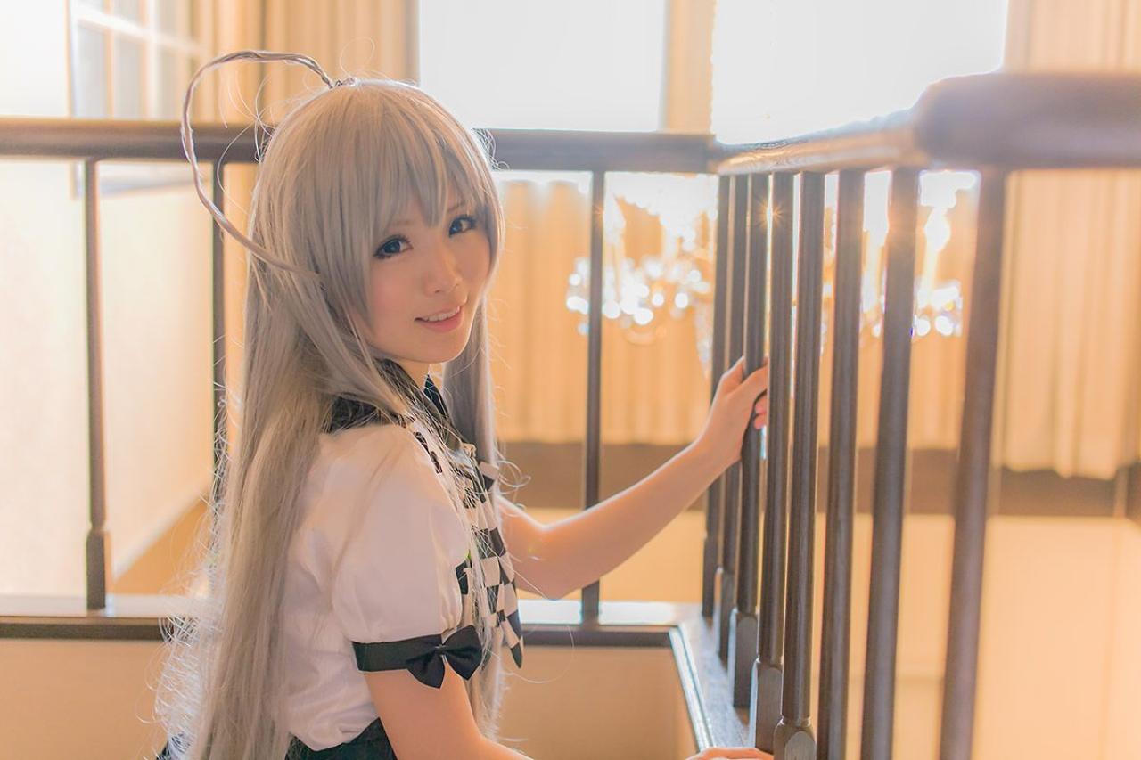 倉坂くるる双手握着楼梯的栏杆，侧身回眸微笑