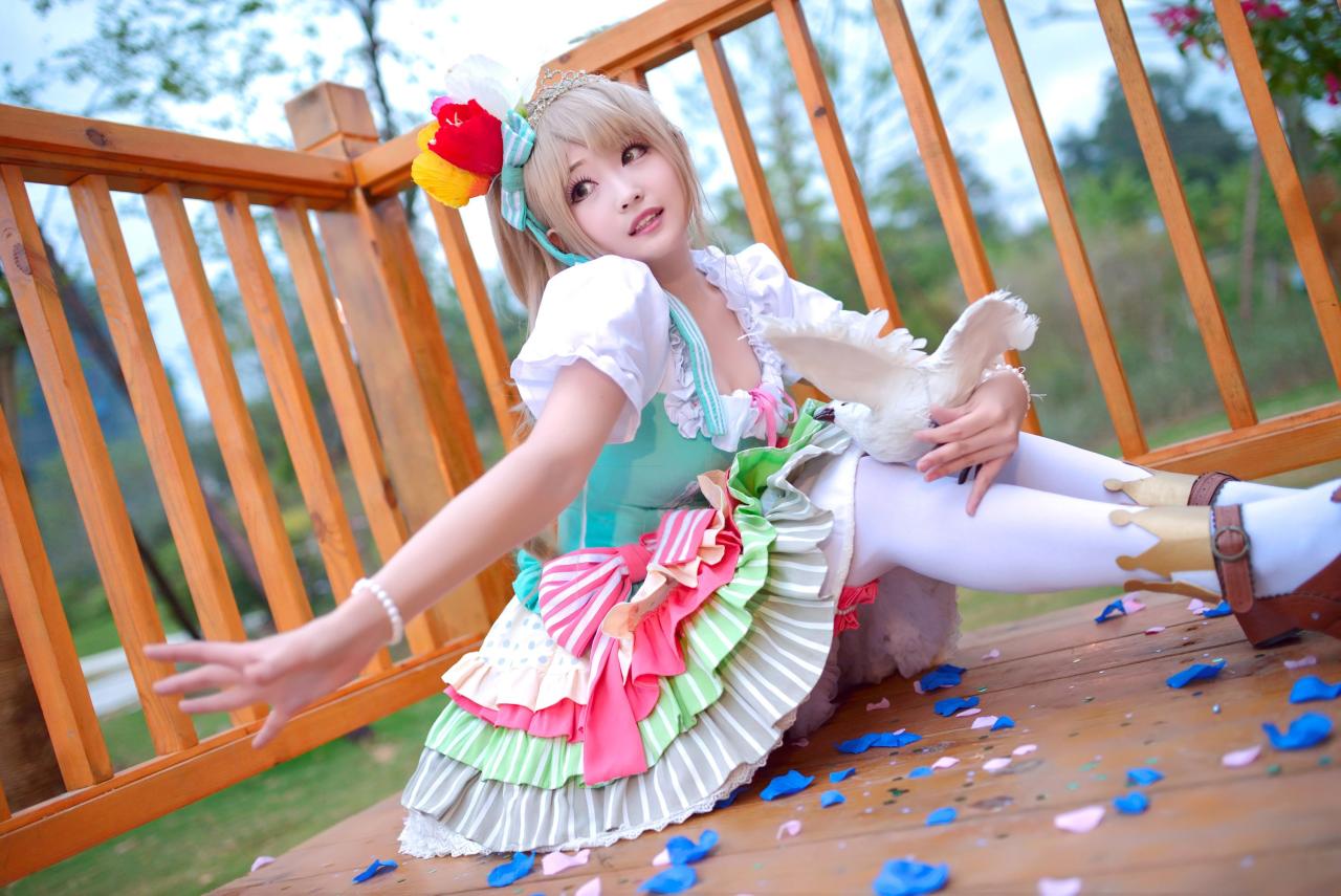 灼漪漪扮南小鸟坐在地板上，怀抱鸽子，伸出右臂，满地散落的花瓣
