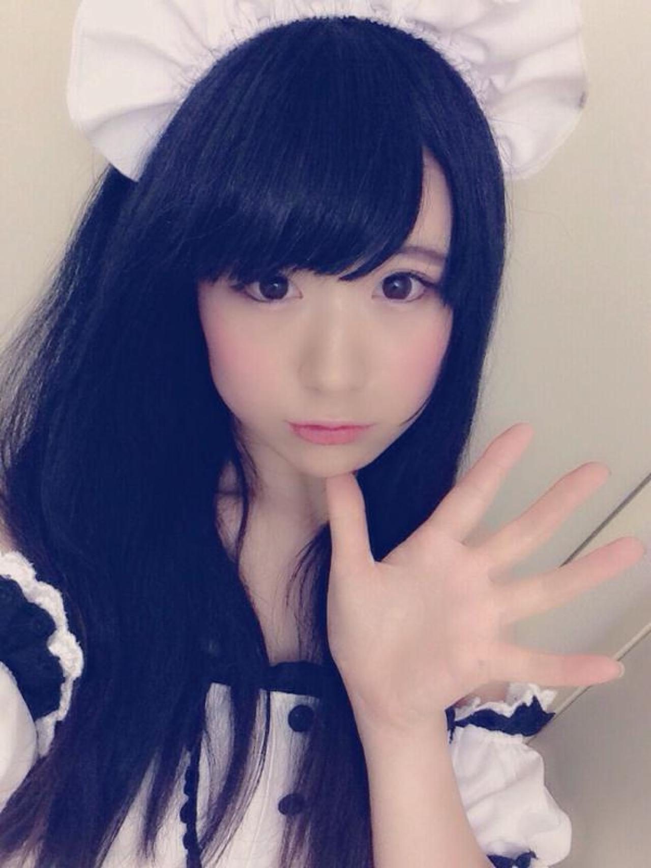 モニ子穿着女仆装左手大拇指抵着下巴，打招呼的手势自拍照