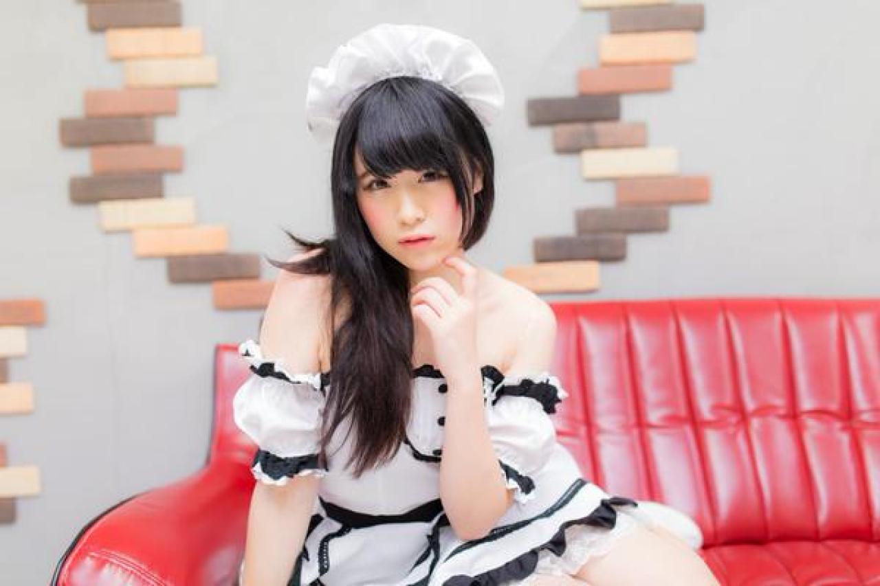 モニ子坐在沙发，左手食指轻抵着下巴，右手撑在沙发上