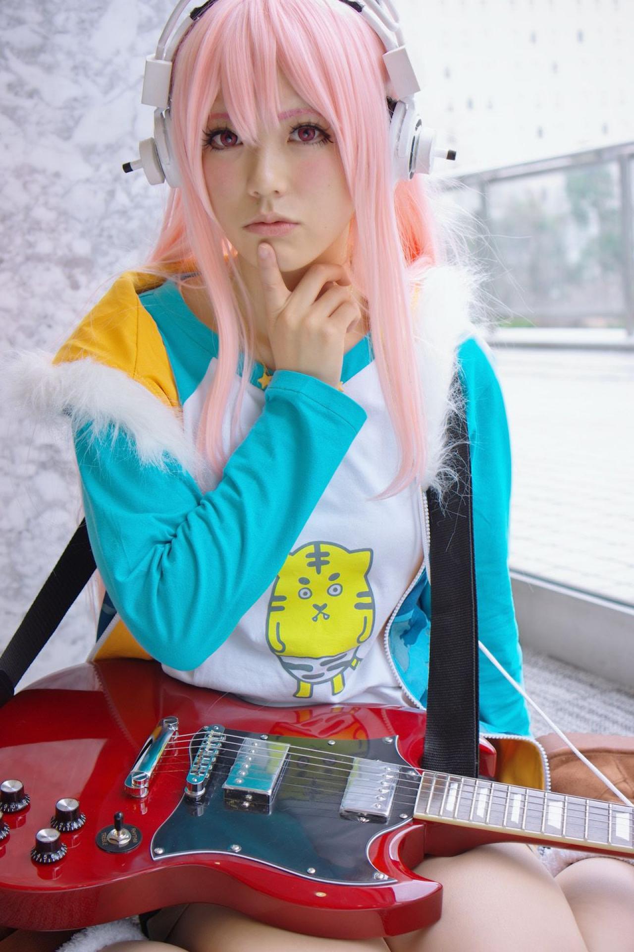 春宮ゆん扮超级索尼子戴着吉他蹲坐在窗前，右手食指贴着下巴