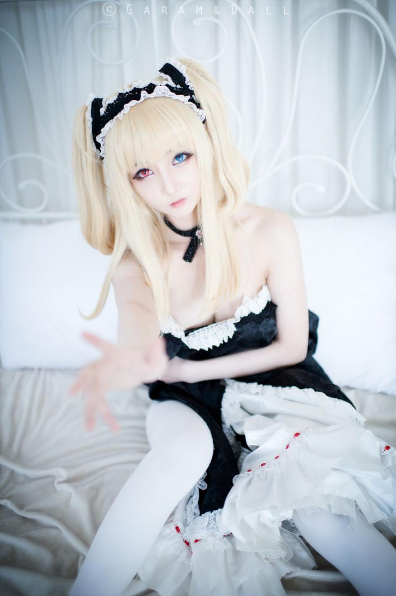 Airi扮羽濑川小鸠坐在床上，伸出右手