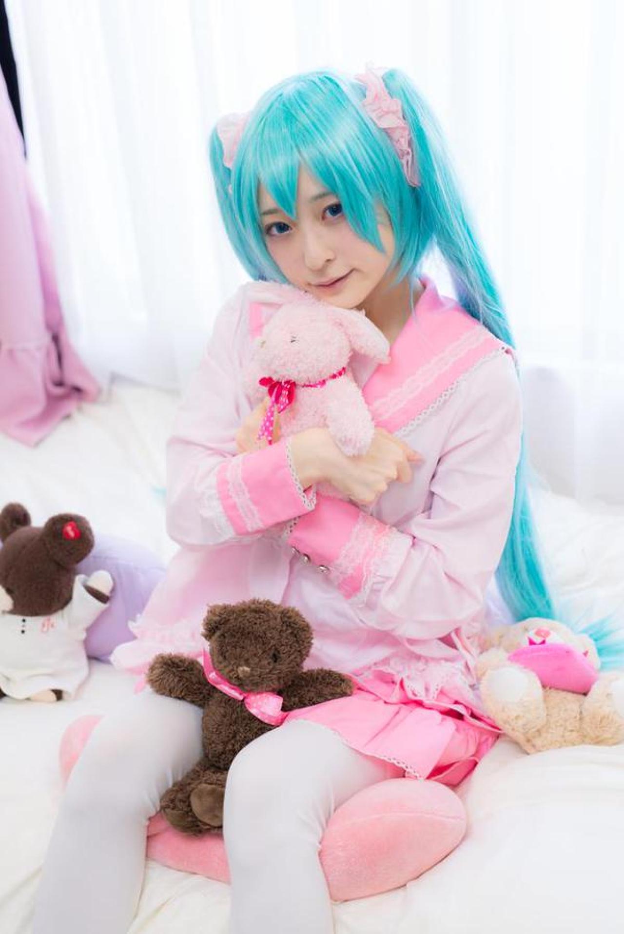 猫守ざーにゃ扮初音未来坐在枕头上，抱着小熊