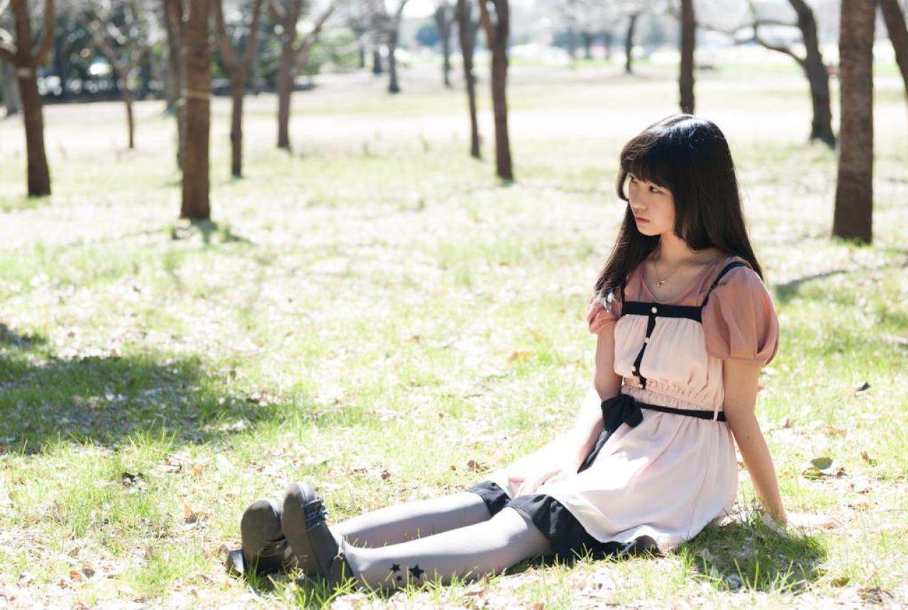 紺乃あすた侧身坐在草地上，右手撑地，左臂放在裙摆上