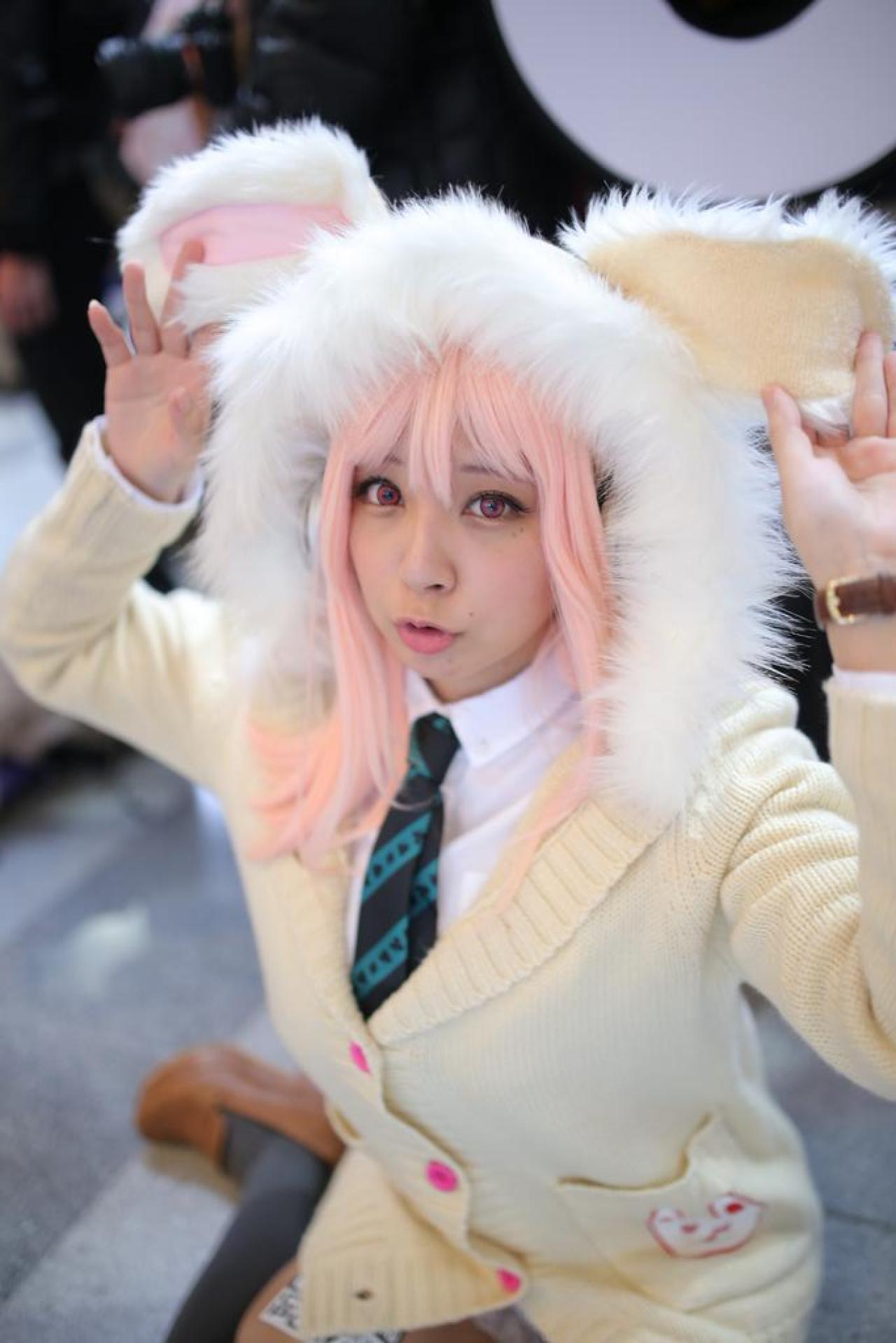 です扮超级索尼子抬起帽子上的兔耳朵，嘟嘴卖萌，蹲姿