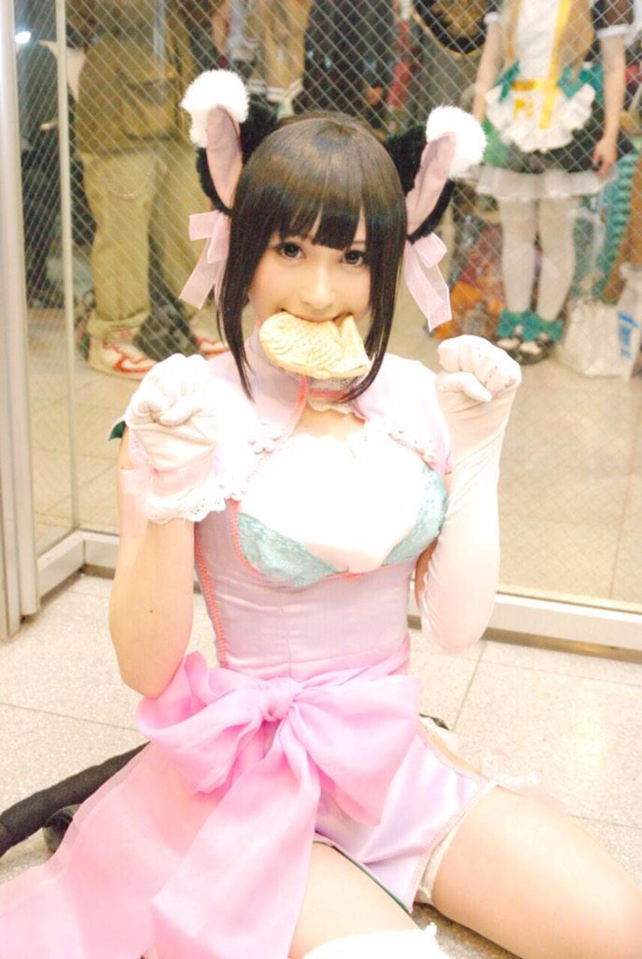 にゃるまー扮小梅咬着鲷鱼烧，双手半握拳扮小猫卖萌，坐姿