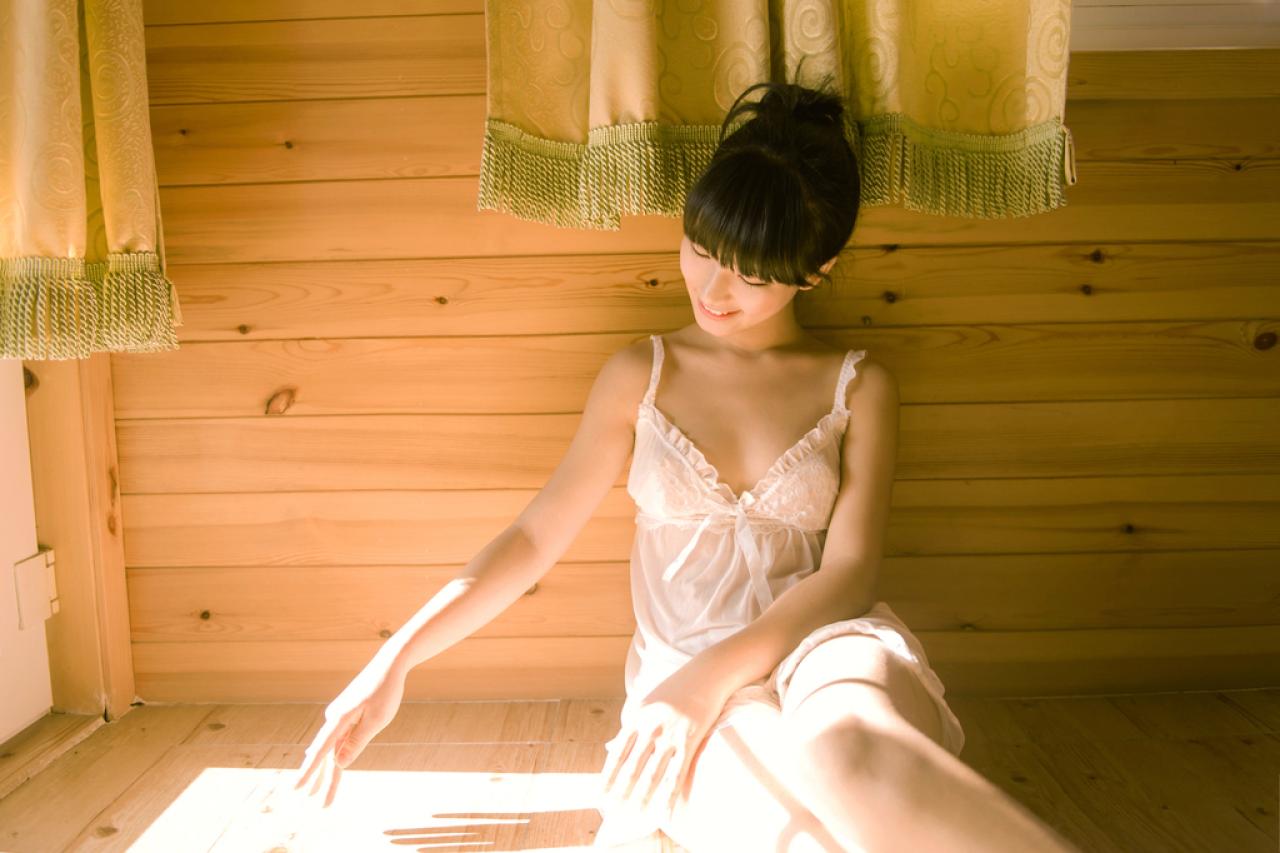 萌宅女靠在木纹墙面上，右手在倾泻的阳光下，摆着影子