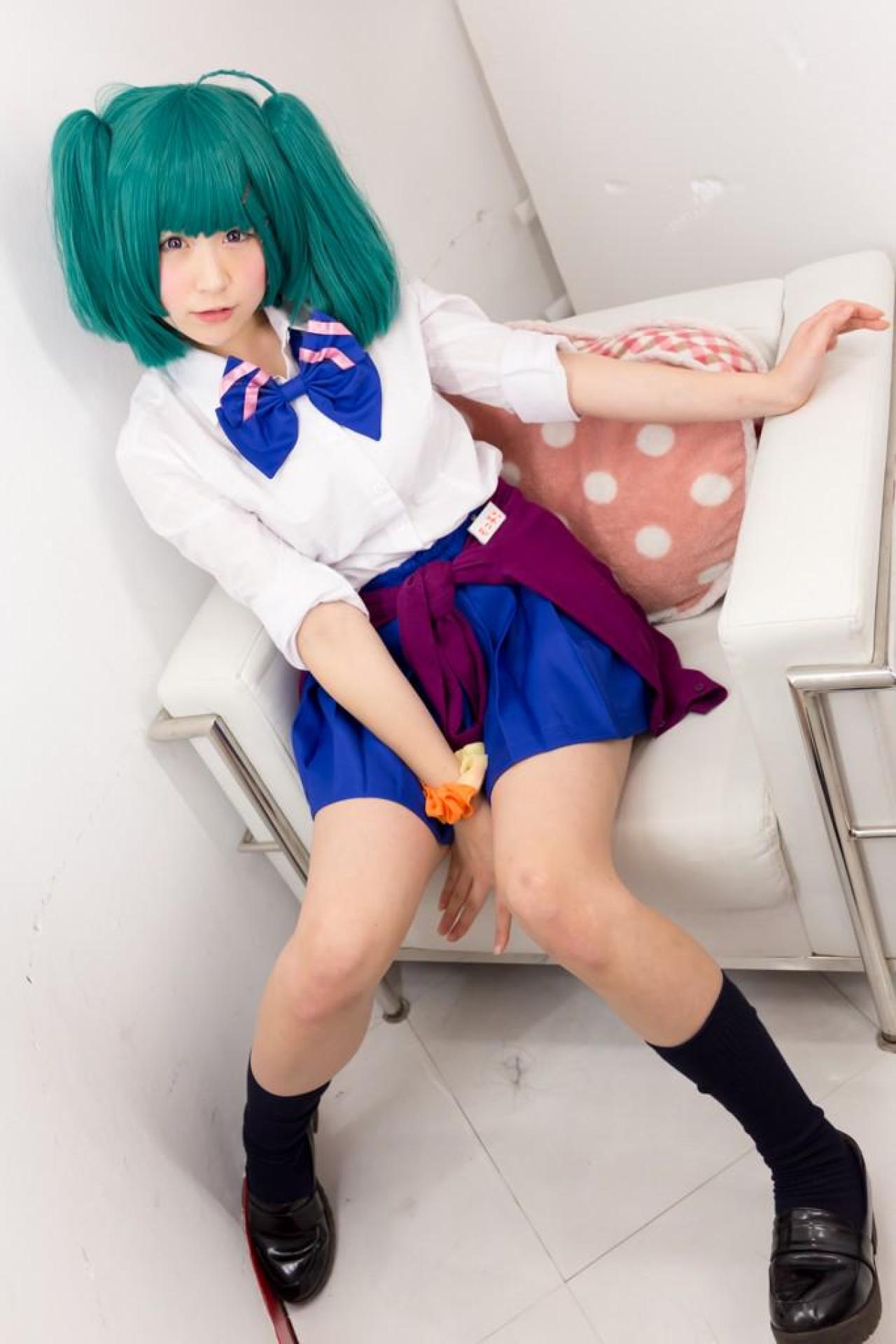 モニ子扮兰花·李坐在放着桃心抱枕的沙发上，左臂放在沙发扶手上，右手撑在沙发垫子上