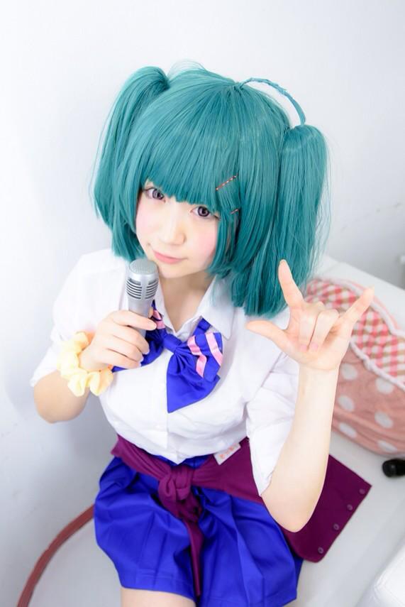 モニ子扮兰花·李坐在沙发，右手拿着麦克风，左手作ILOVEYOU手势