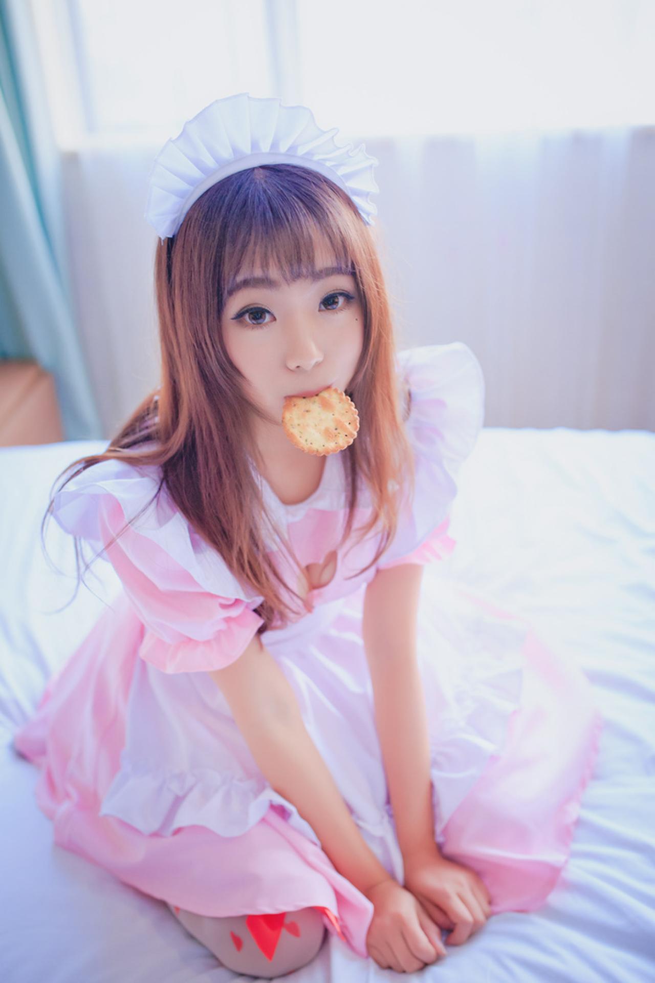 小灵双手搭在裙摆上，轻咬着饼干，扮萌萌哒吃货