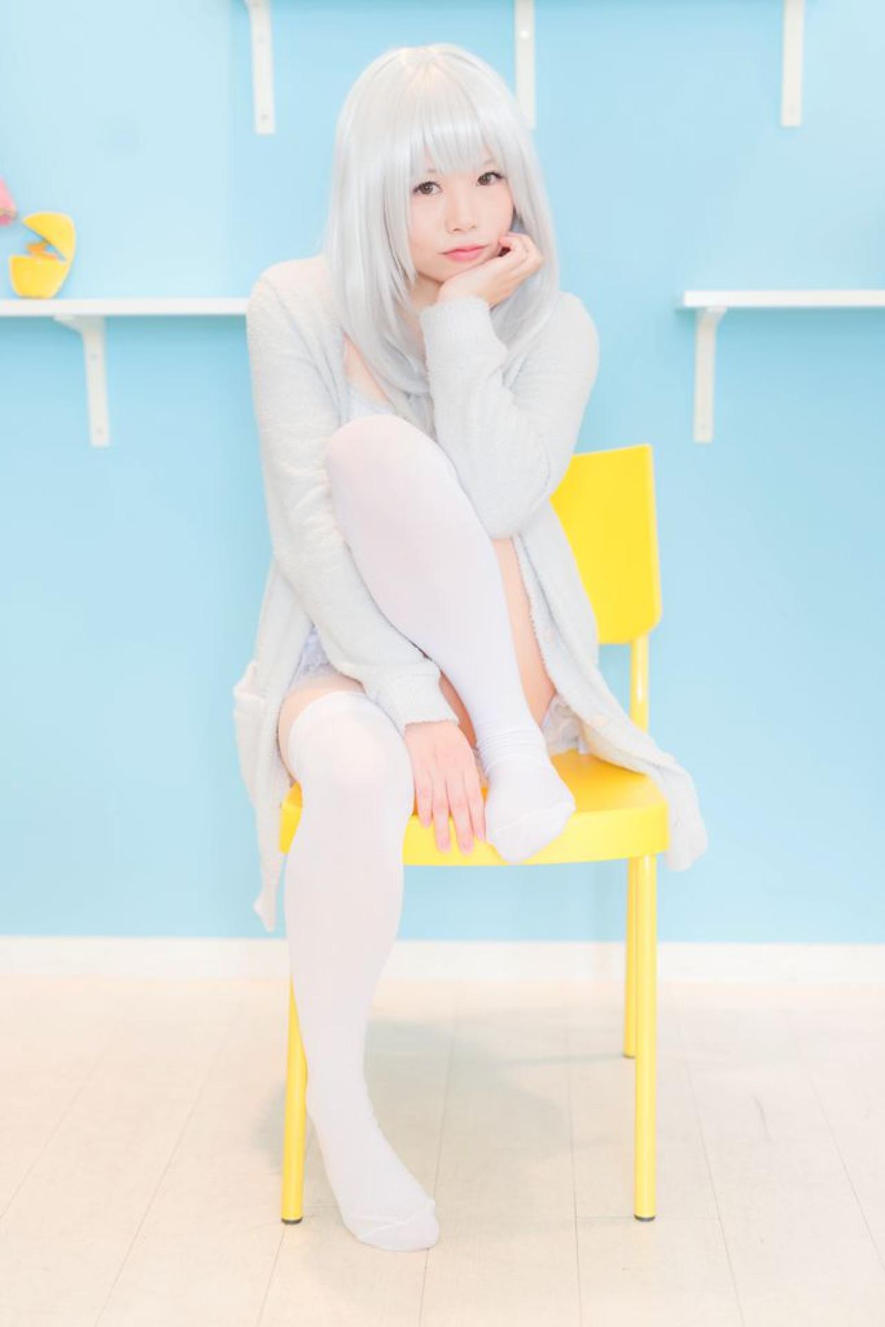 展示墙前，yui提腿坐在黄色椅子上，左手撑着下巴