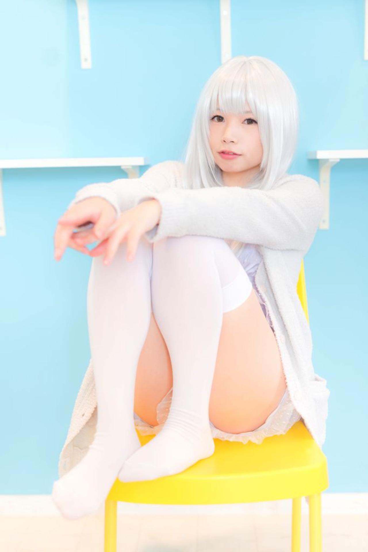 展示墙前，yui提起双腿，坐在黄色椅子上，双手搭在膝盖上
