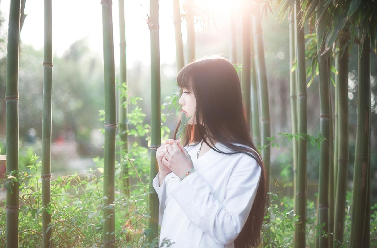 七七双手捏着绿叶站在竹林间