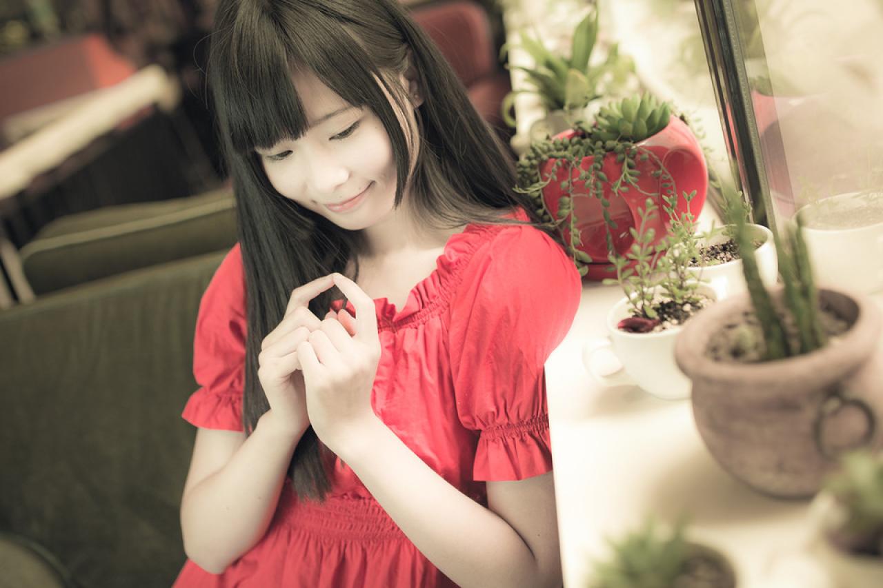 萌妹子侧身靠在窗台，指尖相抵，作心形手势卖萌