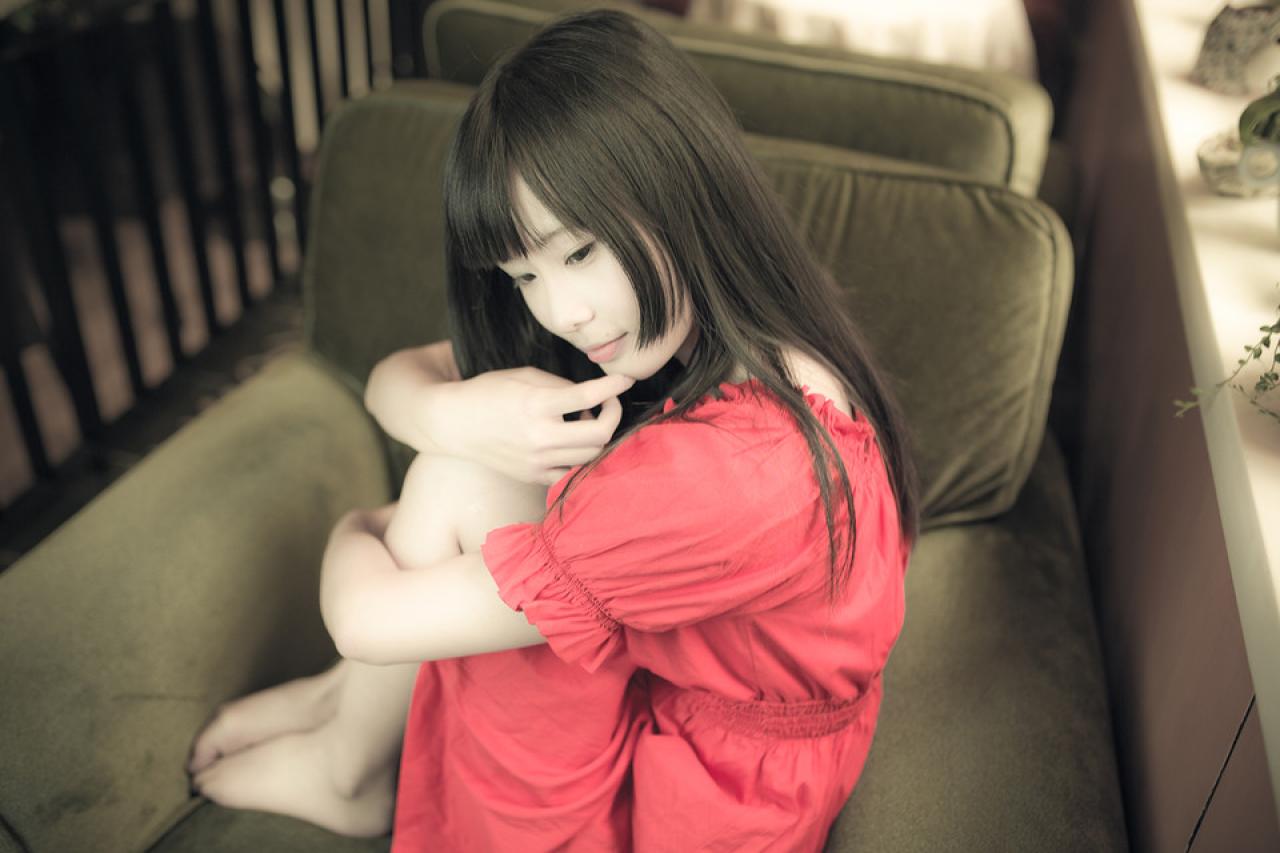 萌妹子怀抱双膝，赤脚坐在沙发上