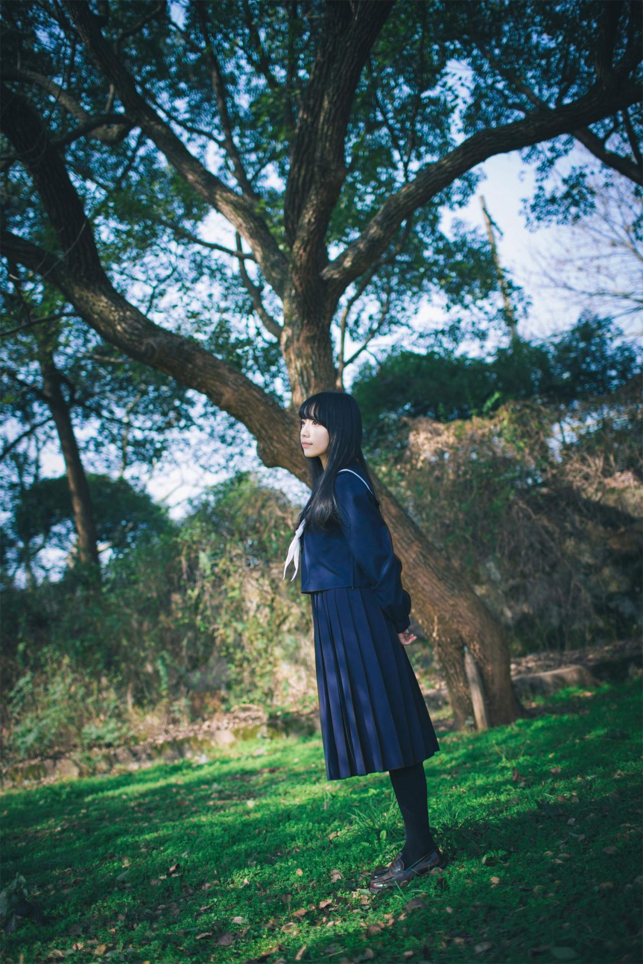 红提子双手背后侧身站在树下的草地上 立幅