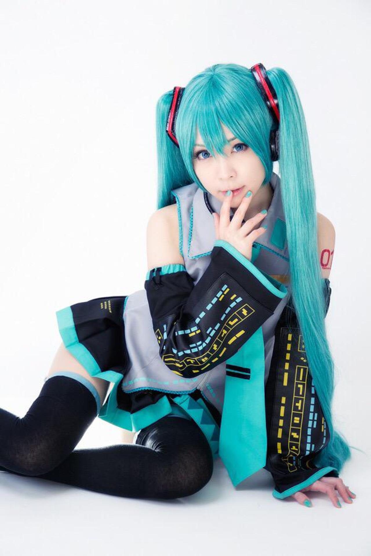 ろき扮初音未来左手撑地，右手扶着唇角，侧身正面照