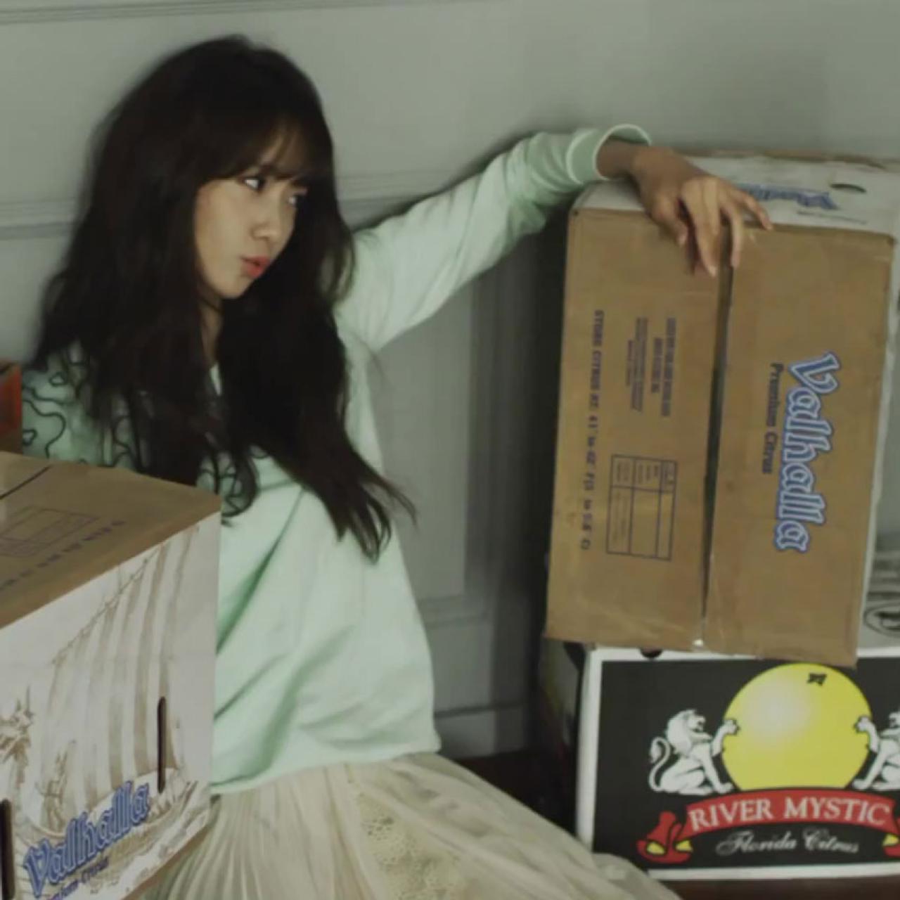 坐在水果箱子旁，搭着箱子嘟嘴卖萌的林允儿表情