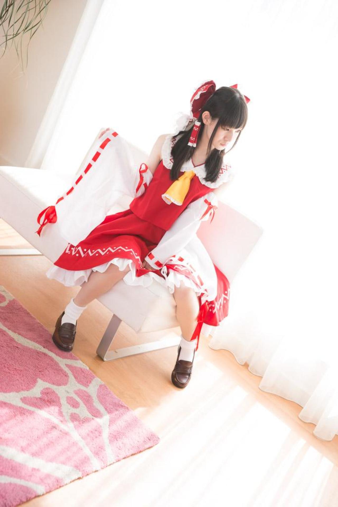 近衛りこ扮博丽灵梦坐在沙发上，抬起右臂，左手握拳撑在裙摆上