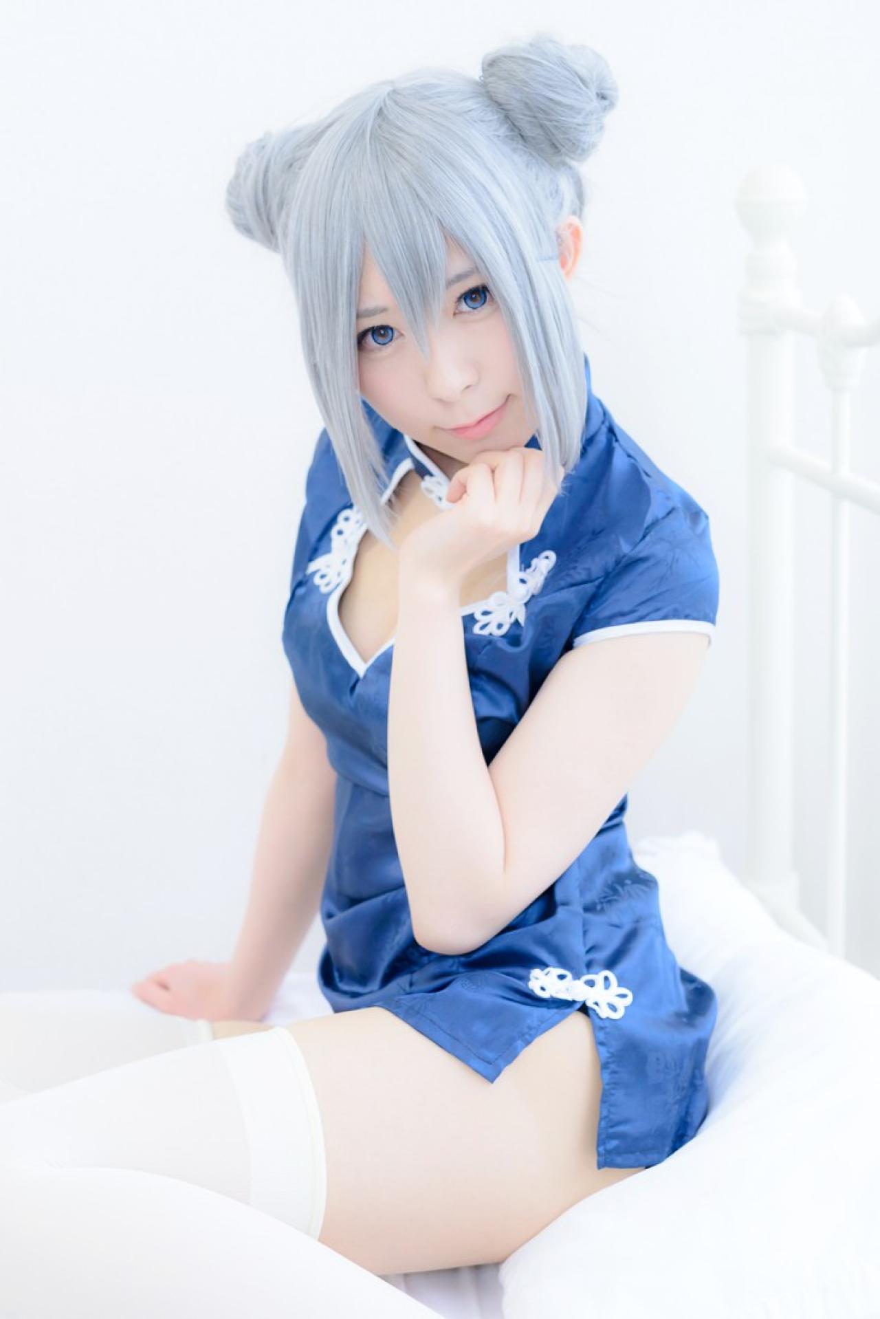 まゆふぁむ坐在枕头上，左手轻扶下巴