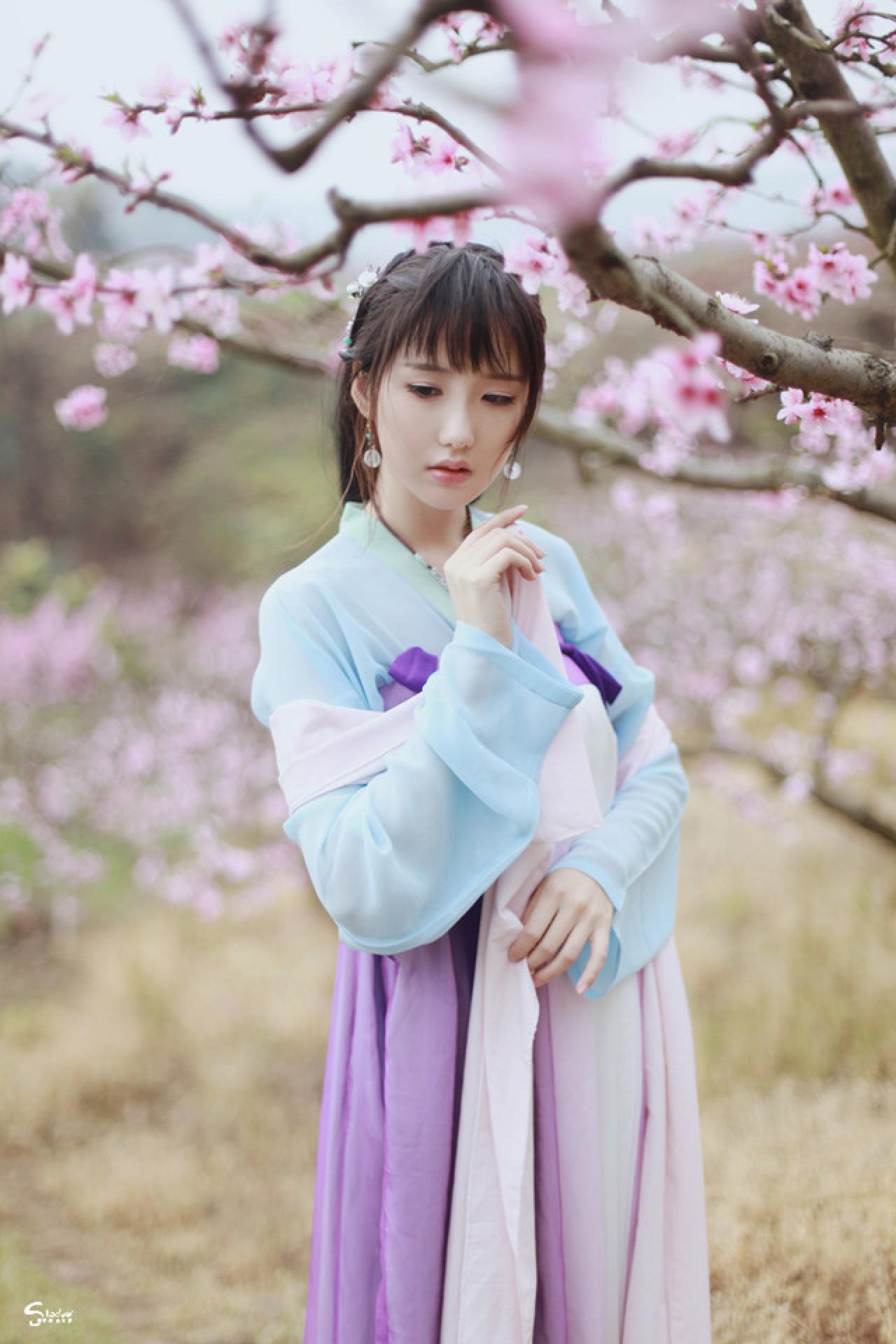 加加代站在桃花树下，右手捏起丝带，左手轻扶