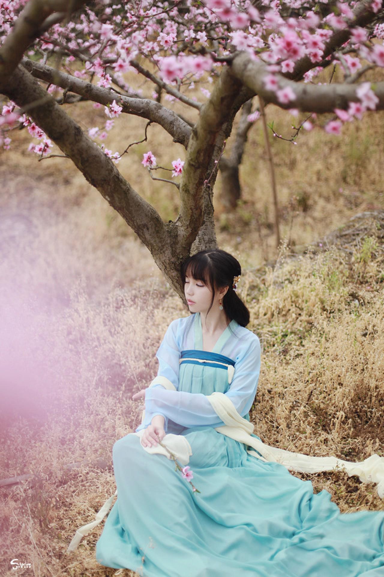 七七捏着桃花枝条靠坐在树下