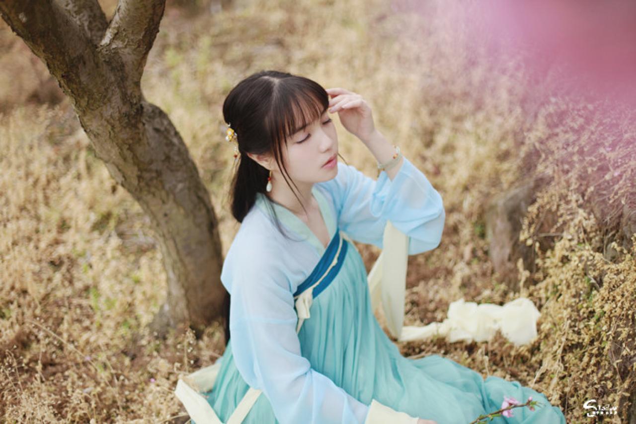 七七坐在桃花树下，闭目仰面，轻扶额头