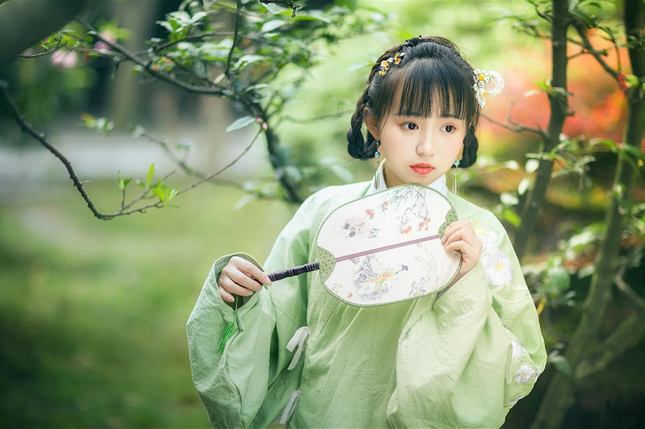 修老虎双手持扇，上半身站姿，略有所思的神情