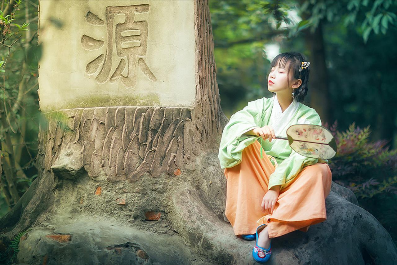 修老虎坐在思源字样的树干旁，轻闭双眼