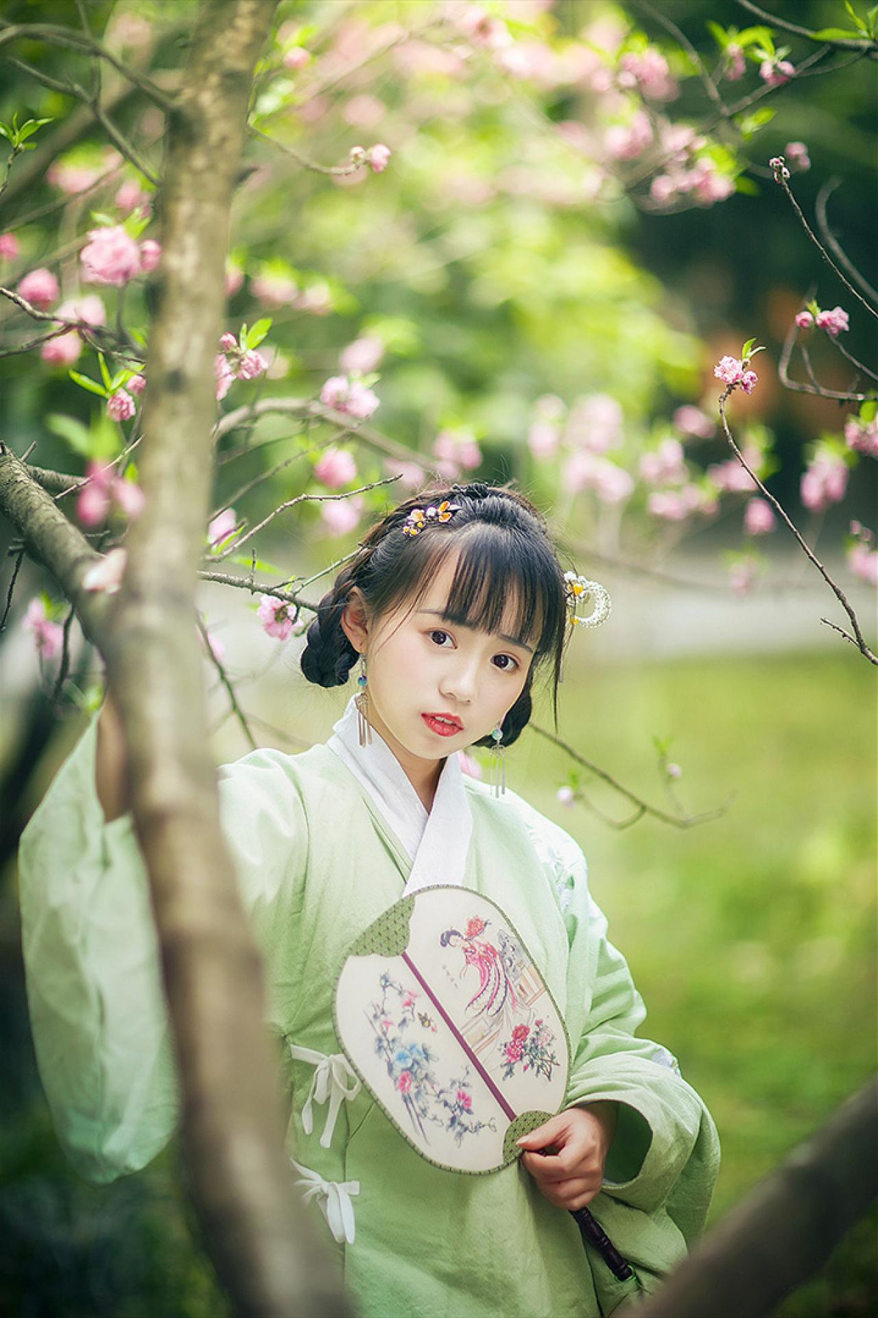 修老虎持扇站在梅花树干的分叉后