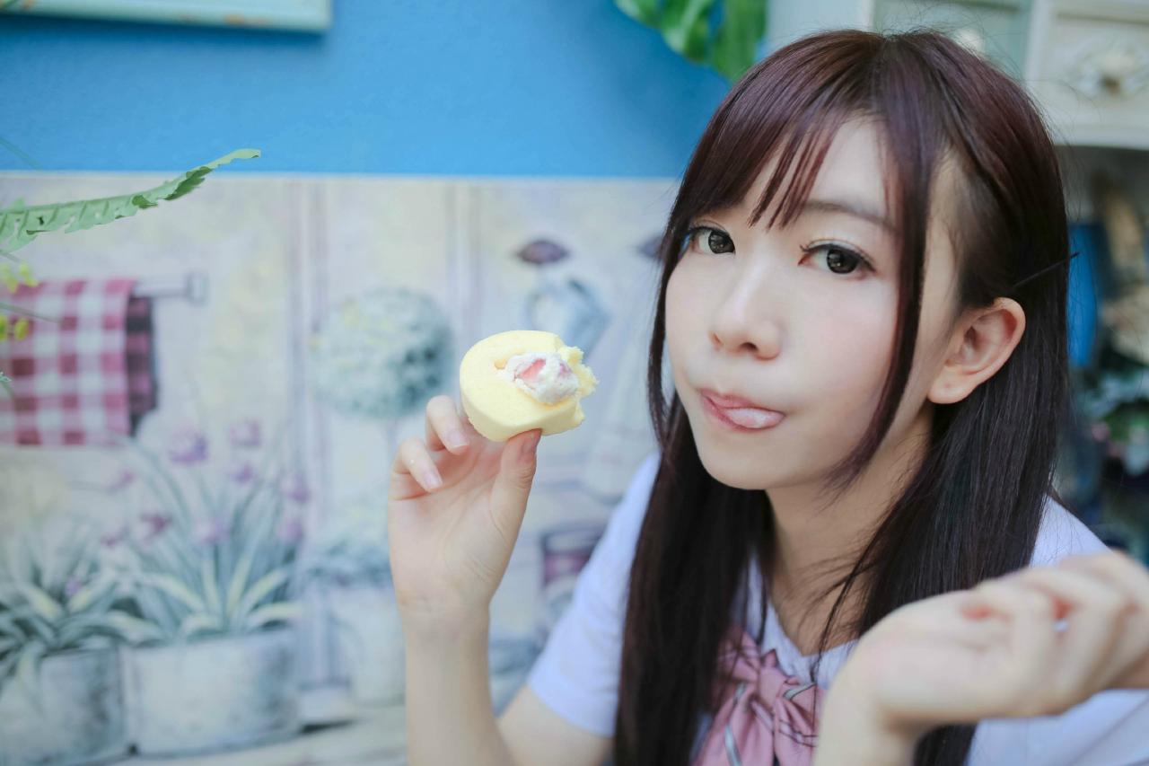 早喵王筱月左手捏着蛋糕，轻吐舌卖萌，看上去很好吃的样子