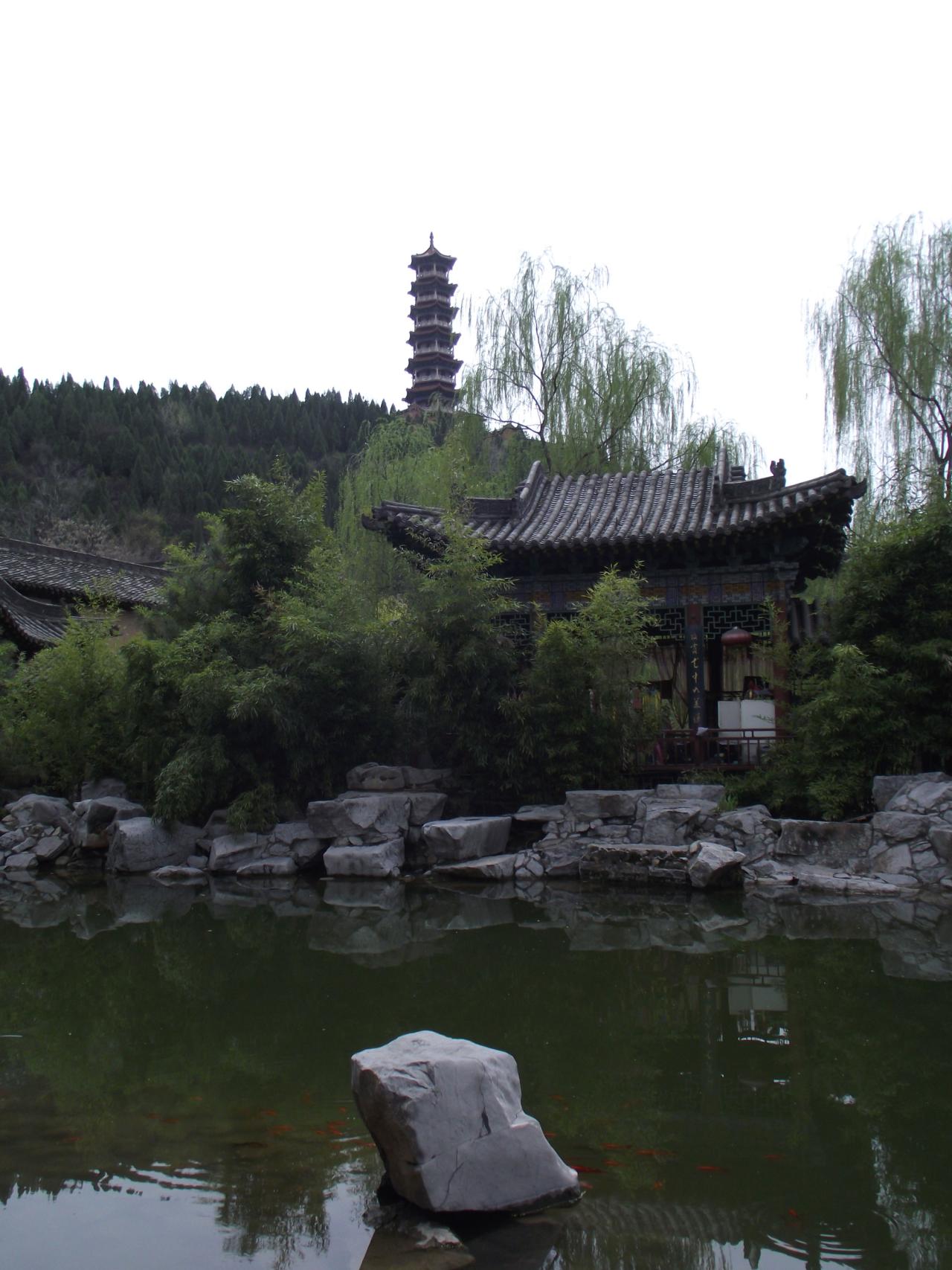 凉亭前的湖面与湖中的红金鱼，远处山上立着塔