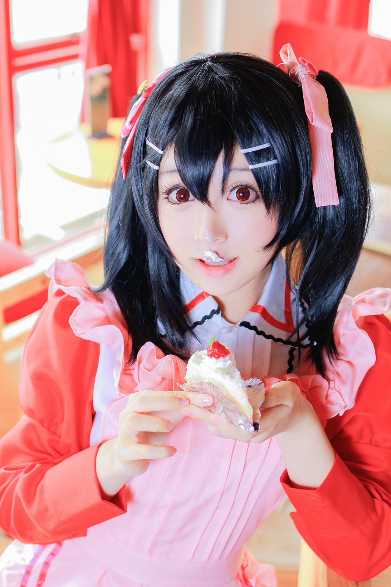 溢灯灯扮矢泽妮可双手捧着奶油蛋糕站在窗前，上嘴唇粘着奶油