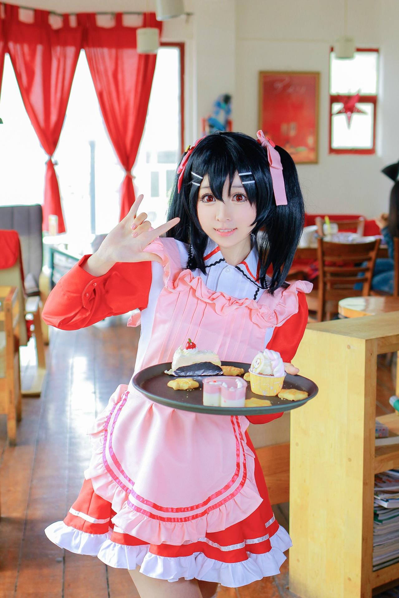 溢灯灯扮矢泽妮可左手端着盘子，右手作ILOVEYOU手势卖萌站在柜子旁