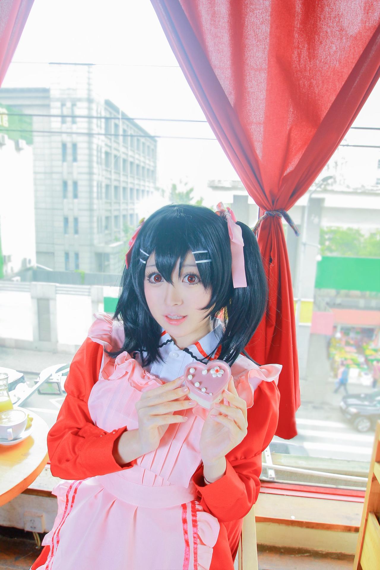 溢灯灯扮矢泽妮可双手捧着心形糖果盒站在窗前的圆桌旁