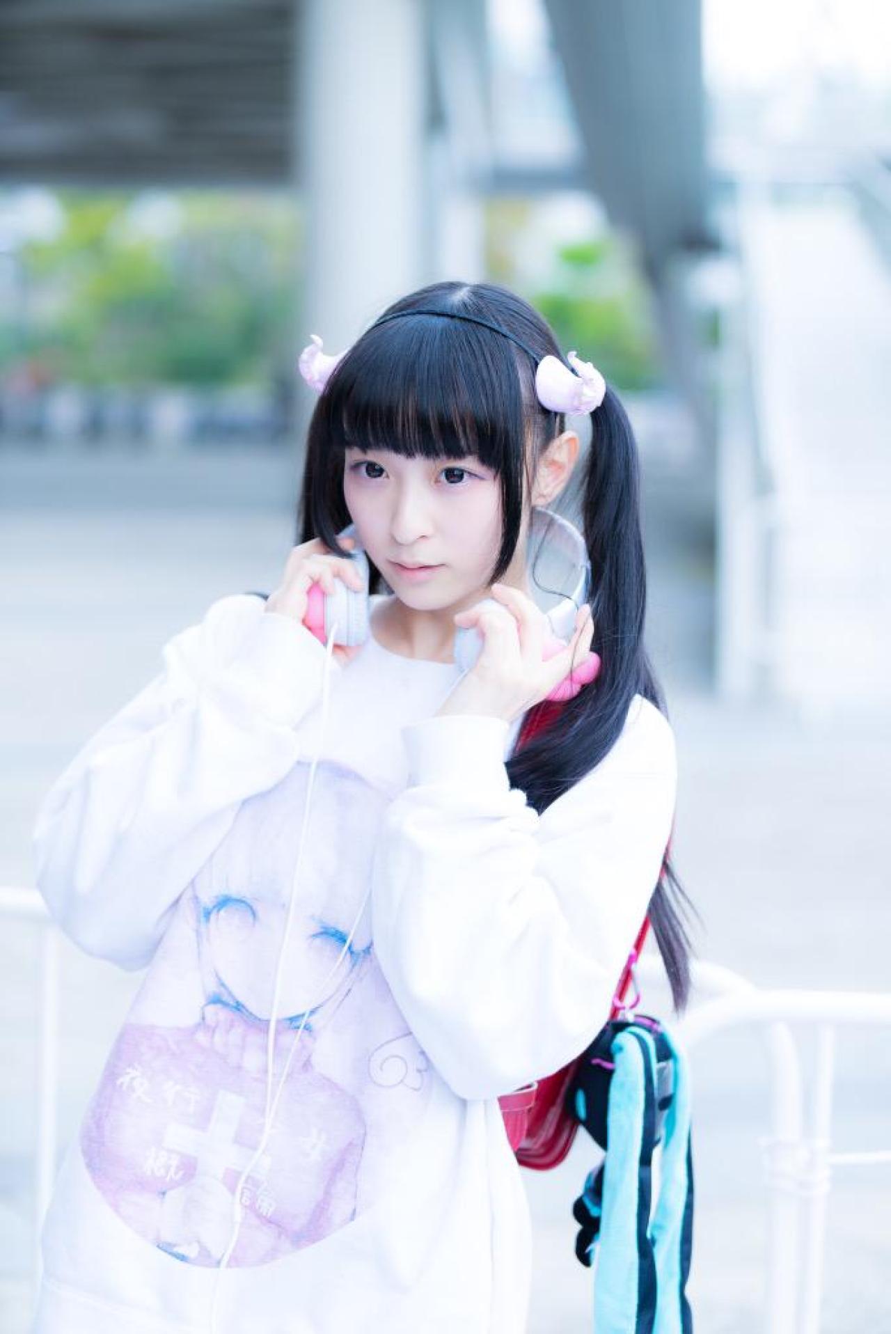 猫守ざーにゃ双手轻握耳机站在栏杆前 3/4侧面