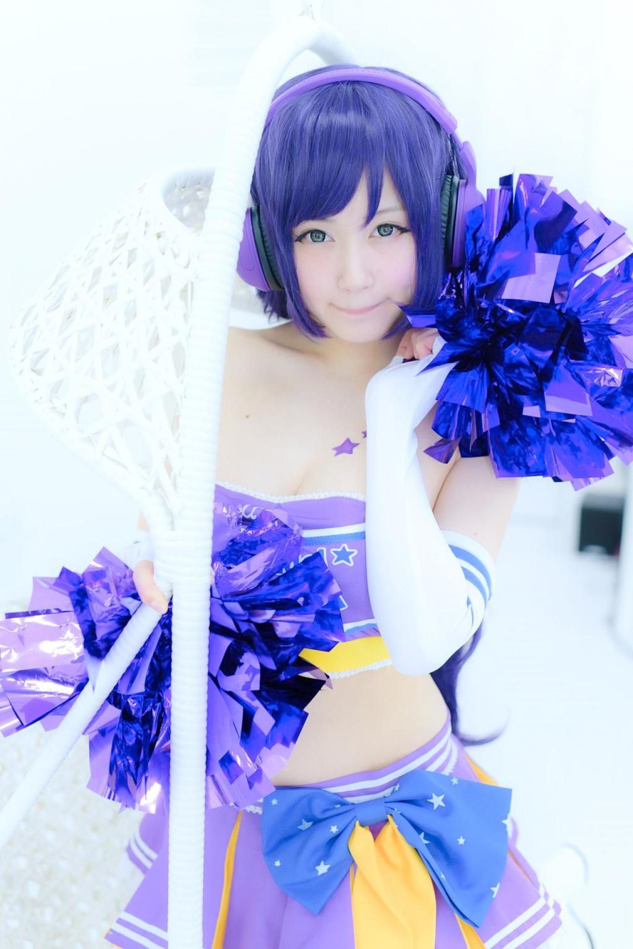 御伽ねこむ扮东条希站在吊篮旁，右手扶着栏杆，左手拿着拉拉队花球