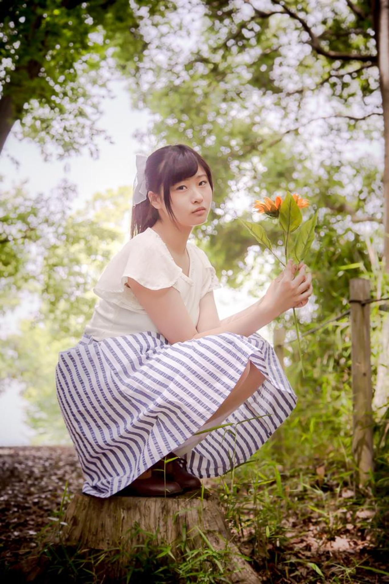 まいあむさん双手捧着鲜花蹲在树桩上