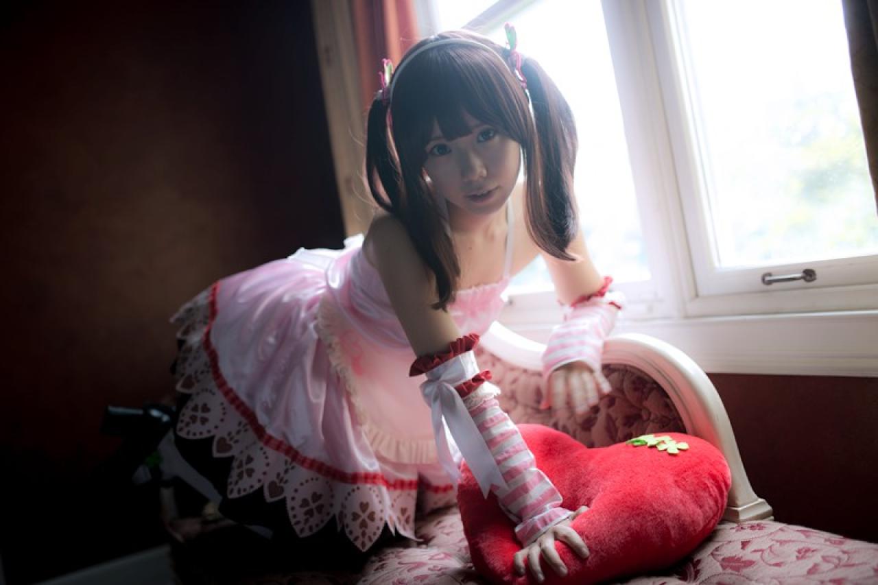 Reco扮绪方智绘里扒在窗旁的沙发床上，左臂床背，右手扶在桃心抱枕上