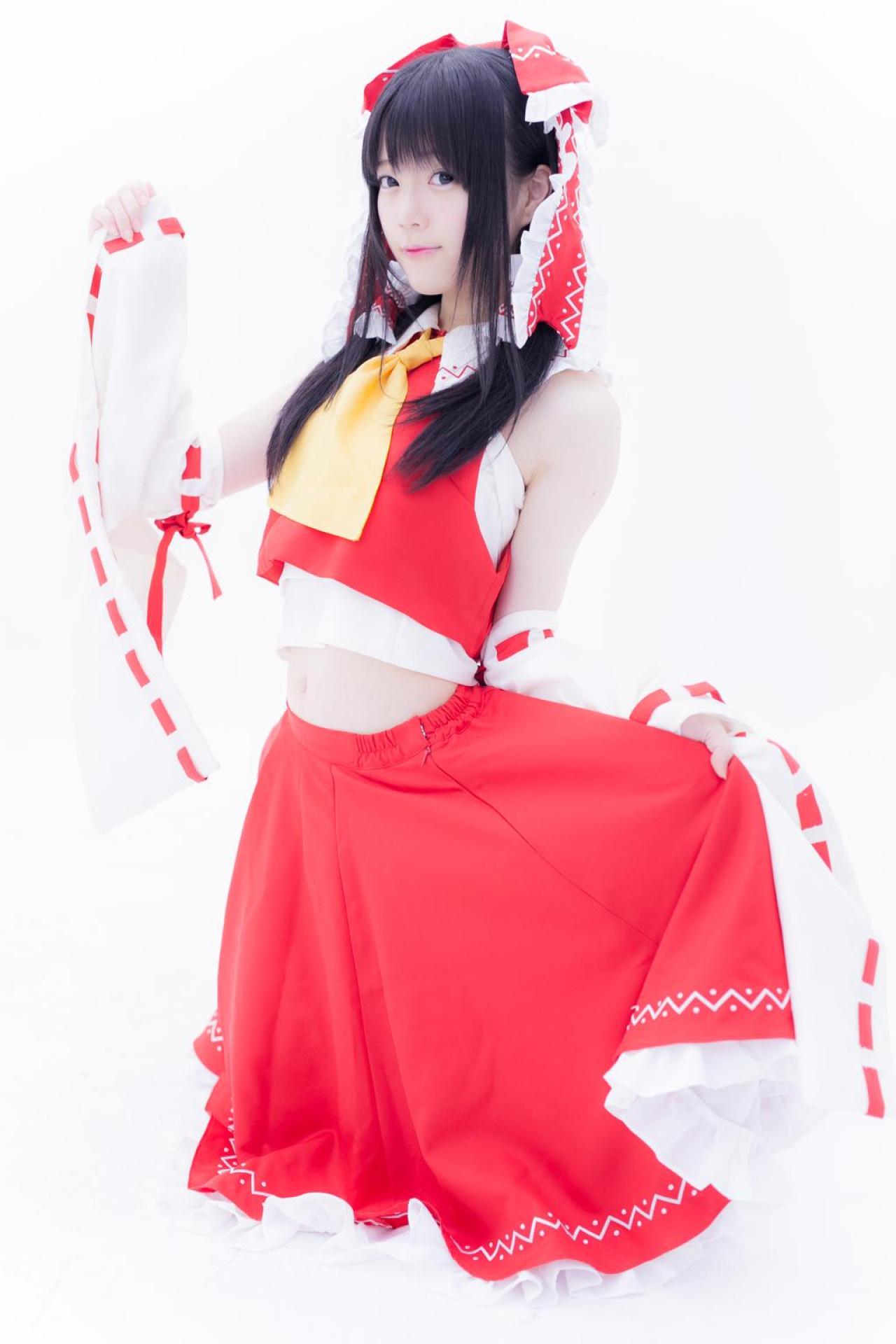 まきろん扮博丽灵梦跪在地上，左手拎起裙摆，抬起右臂