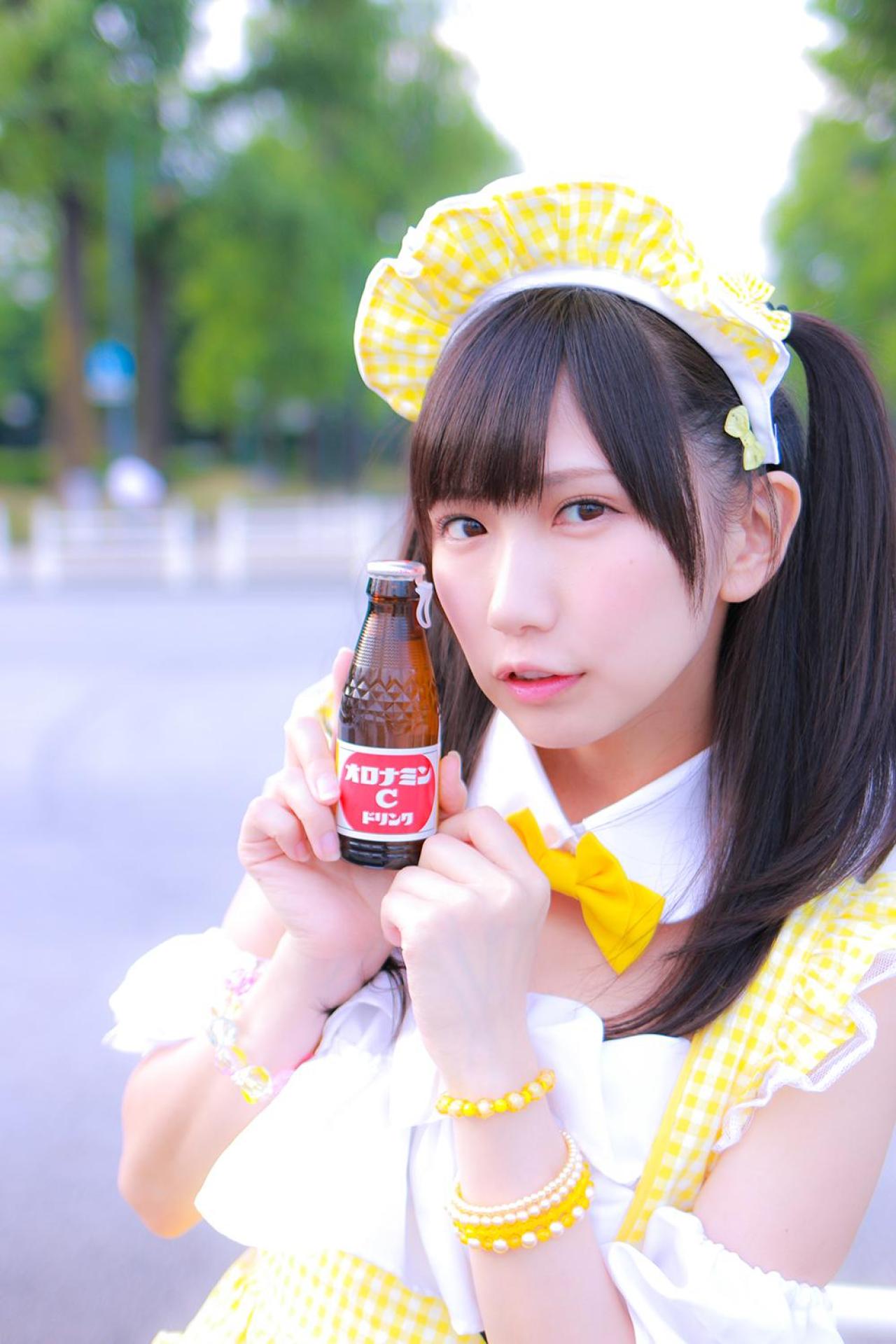 小日向くるみ扮女仆双手将ORONAMIN C（オロナミンC）饮料捧在胸前，贴在脸颊右侧 上半身正面