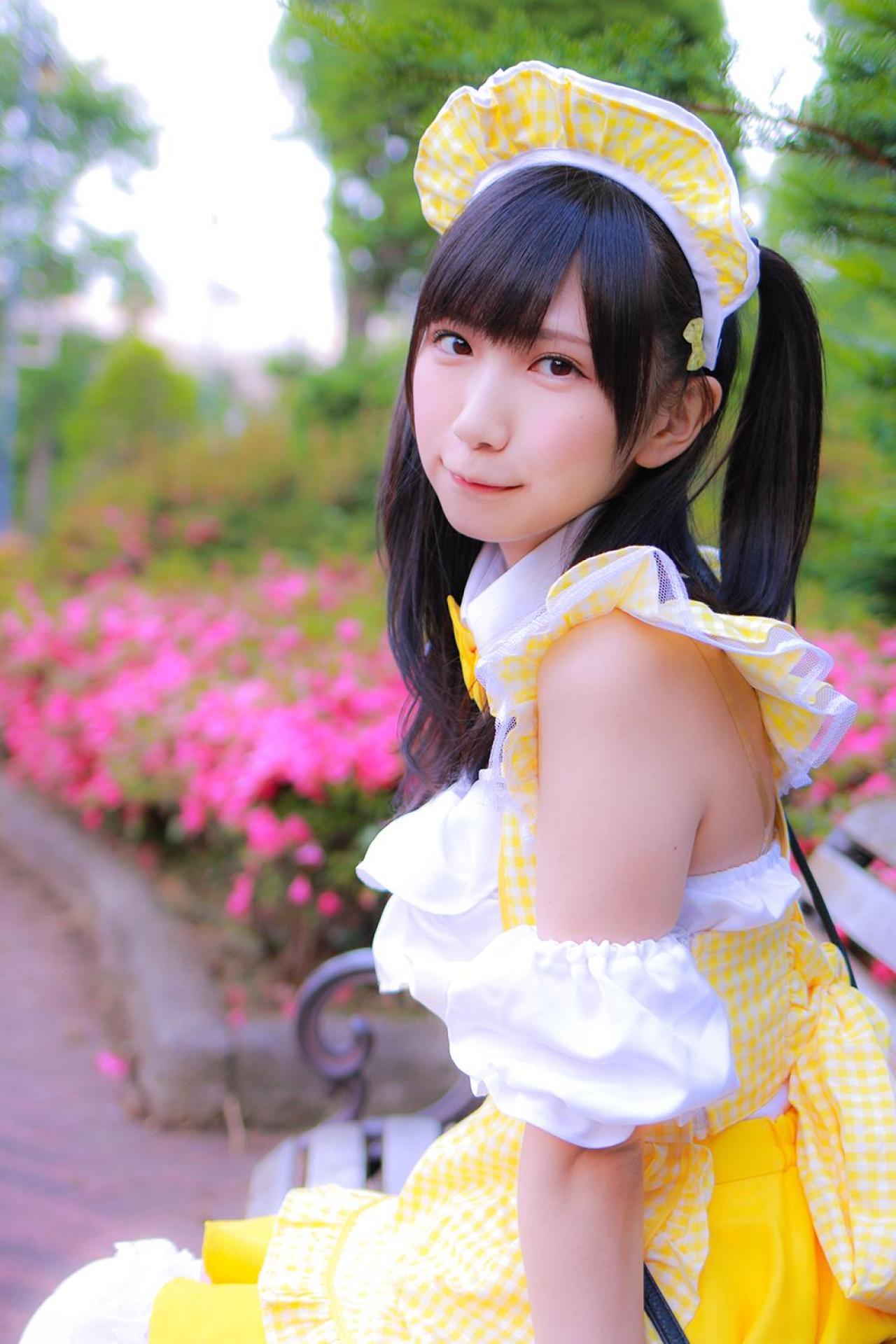 小日向くるみ扮女仆侧身坐在鲜花旁的长椅上，抿嘴卖萌