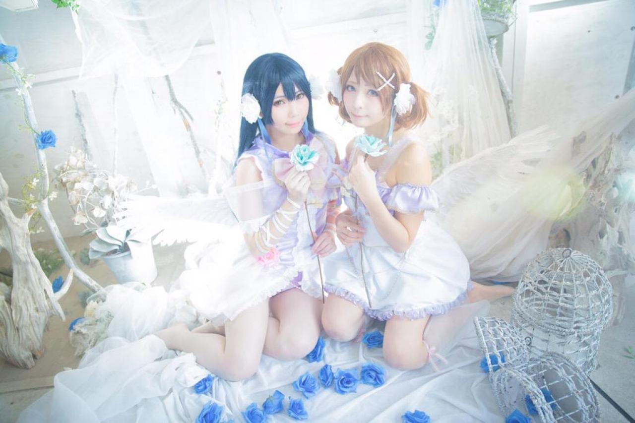 ステラ扮园田海未和かりちゃ扮小泉花阳两人靠在一起，手捧蓝色花束，跪坐在地板上