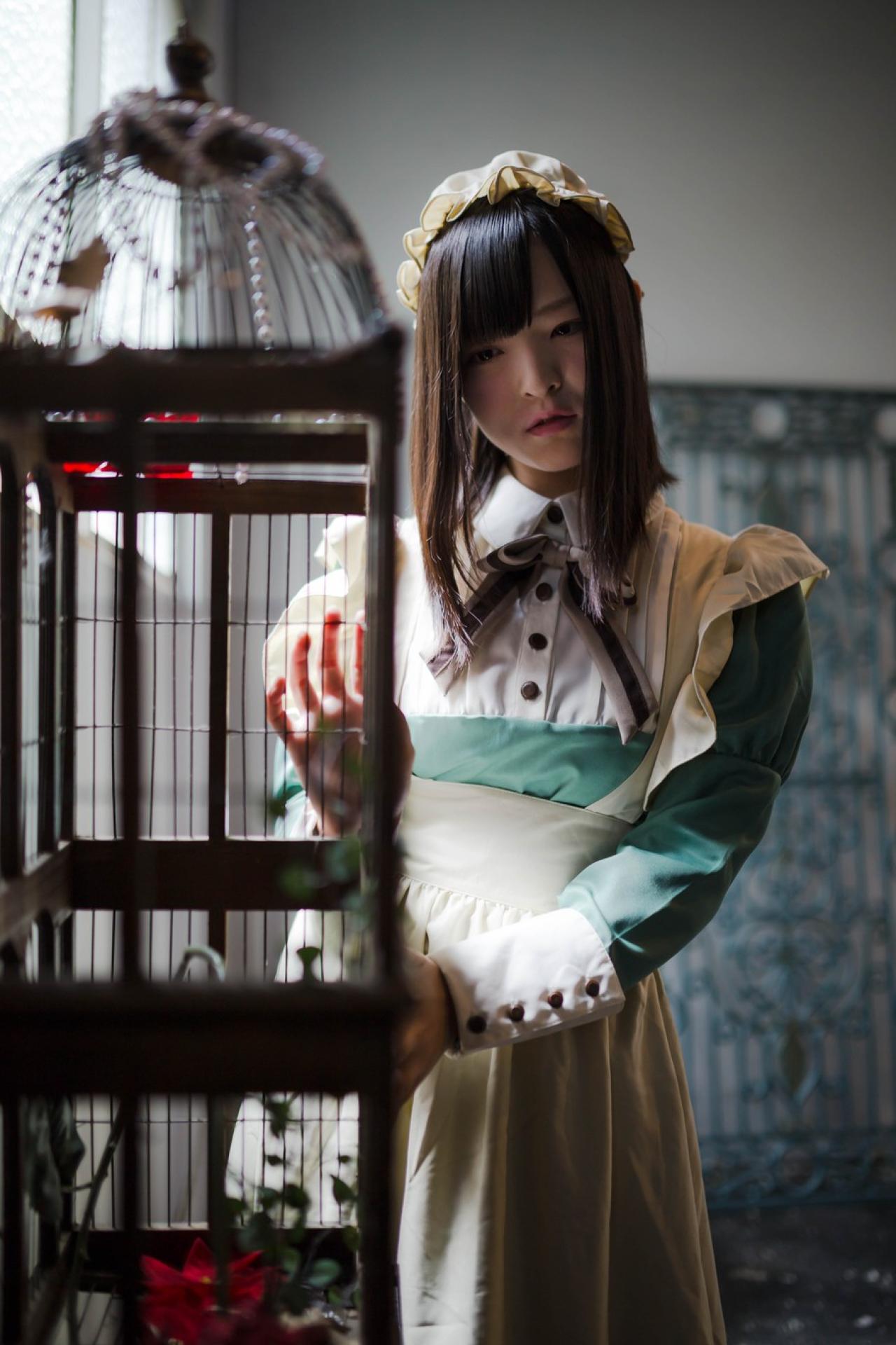 肉球あやと双手轻扶鸟笼，歪着头站在一旁