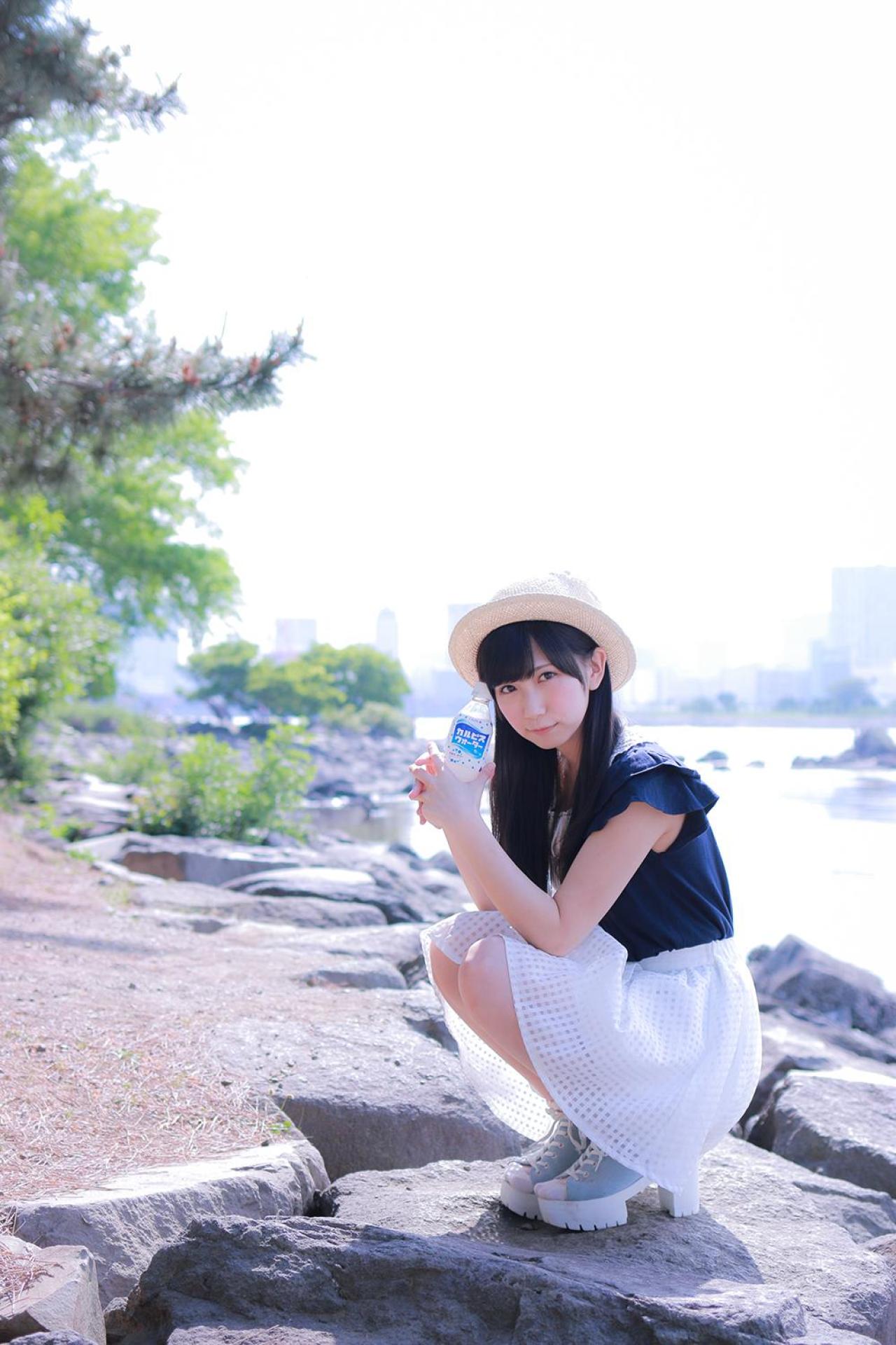 小日向くるみ双手举着可尔必思饮料蹲在河边