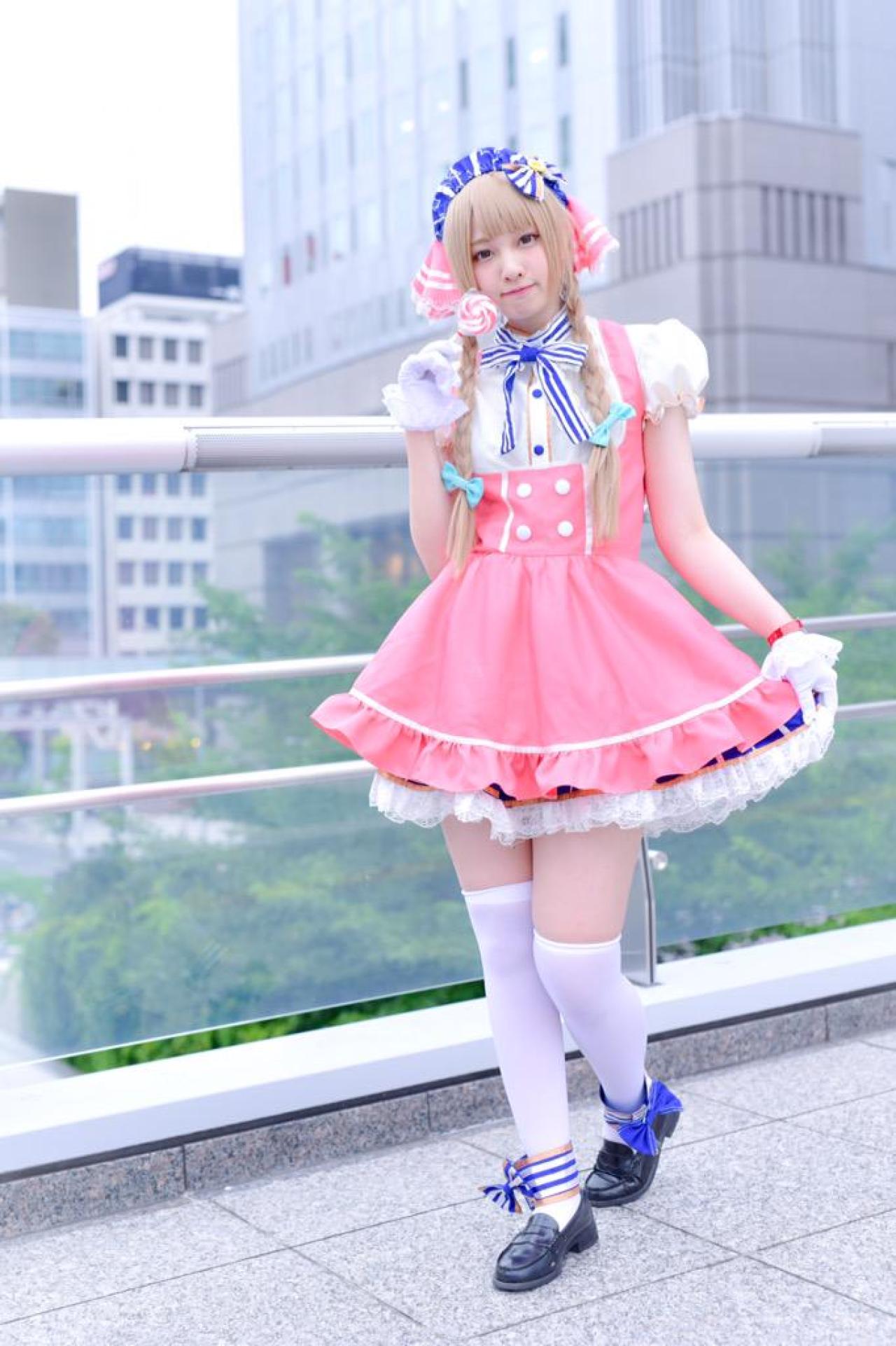 玖音さん扮南小鸟右手拿着棒棒糖，左手拉起裙摆 站在围栏前