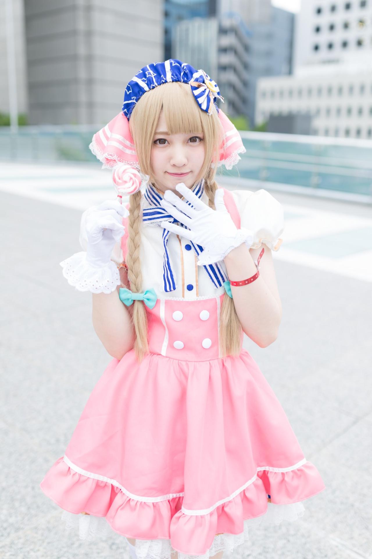 玖音さん扮南小鸟右手拿着棒棒糖，左手五指张开放在下巴前 正面站姿